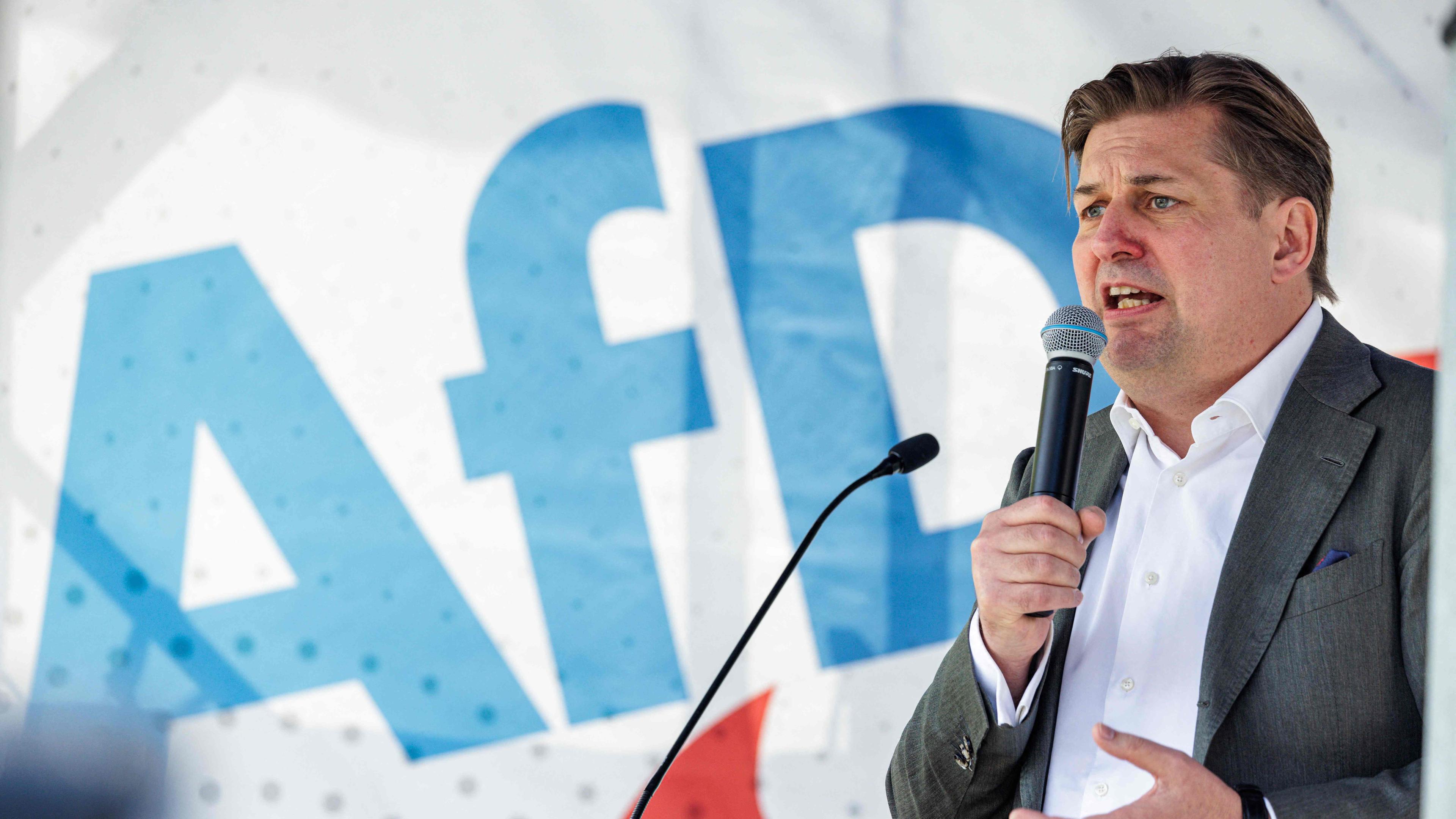 Europa-Spitzenkandidat Krah (AfD) bei einem Wahlkampfauftritt. Hinter ihm das Logo der AfD.