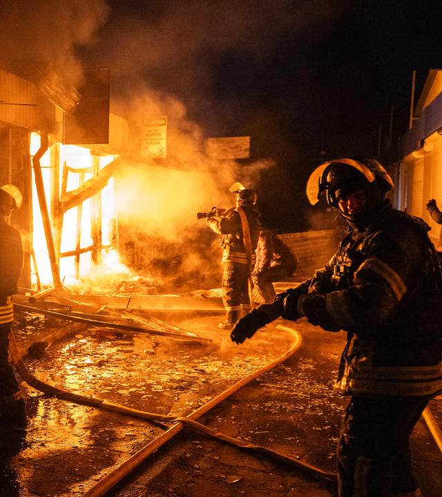 Feuerwehrleute arbeiten daran, die Flammen einzudämmen, die aus dem zentralen Markt in Kramatorsk aufsteigen, nachdem ein russischer Drohnenangriff das Gebiet in Brand gesetzt hat. 