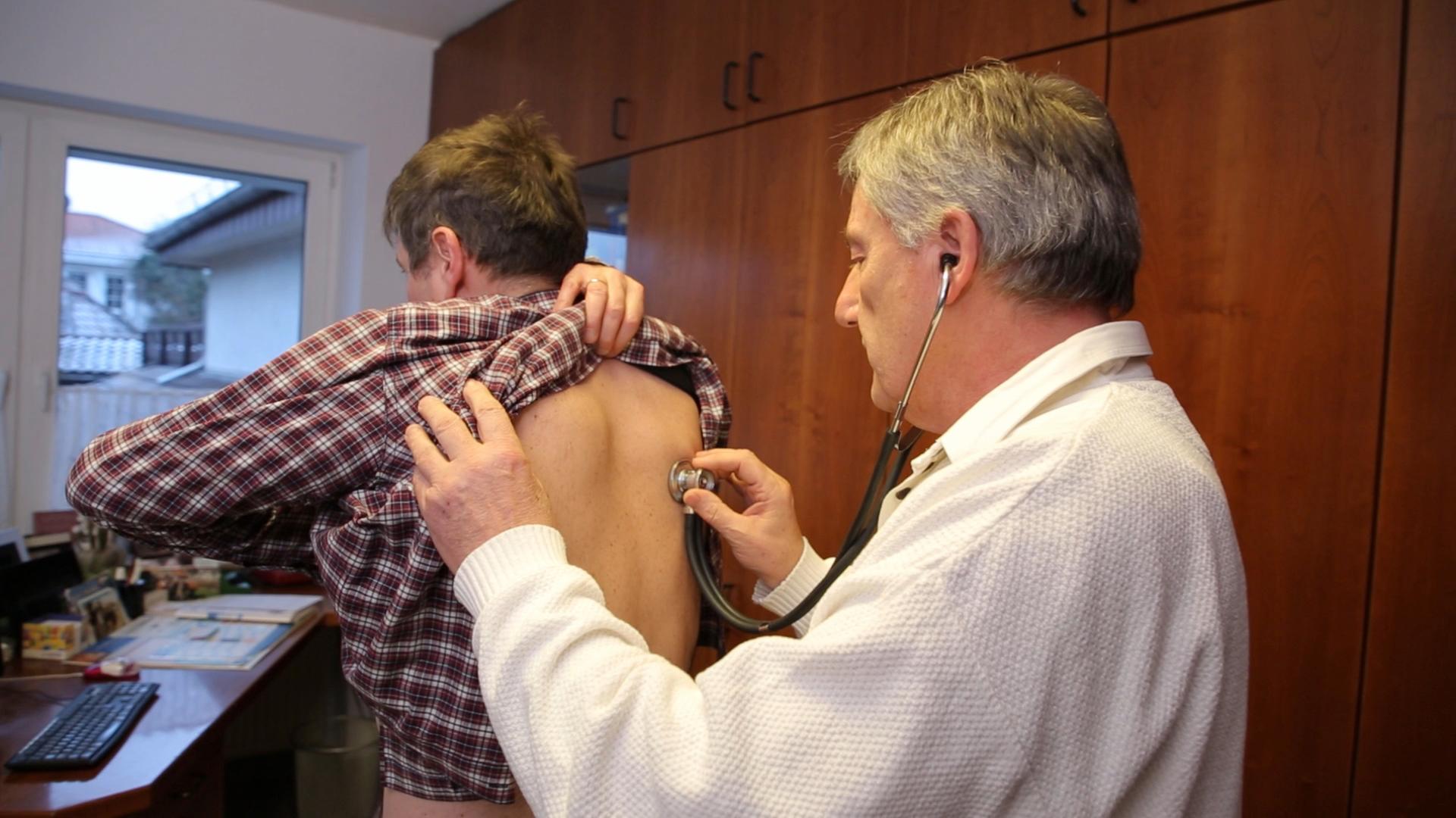 Patient lässt sich von Arzt am Rücken untersuchen