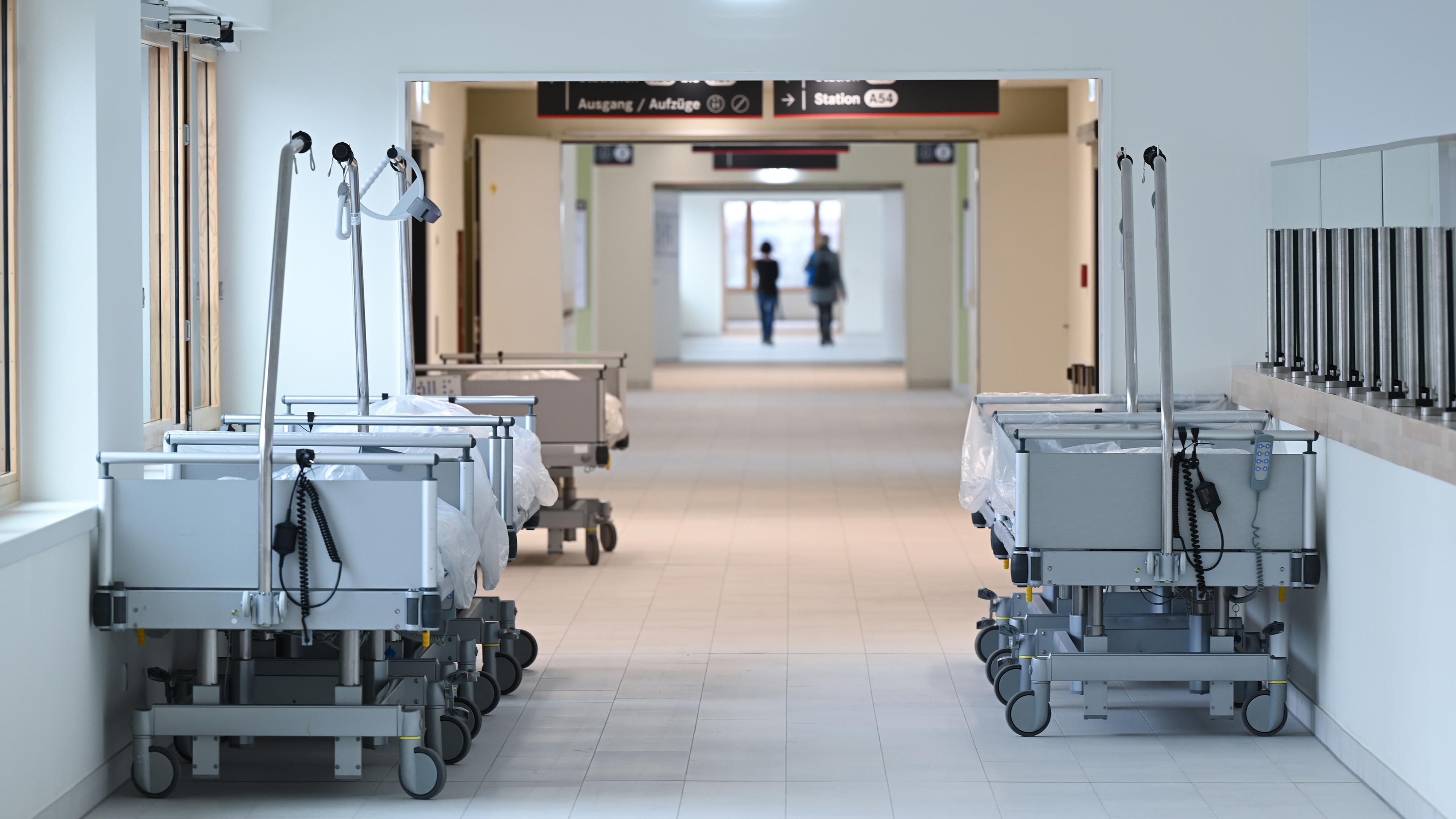 Leere Krankenbetten stehen in einem Neubau auf einen Klinikflur.