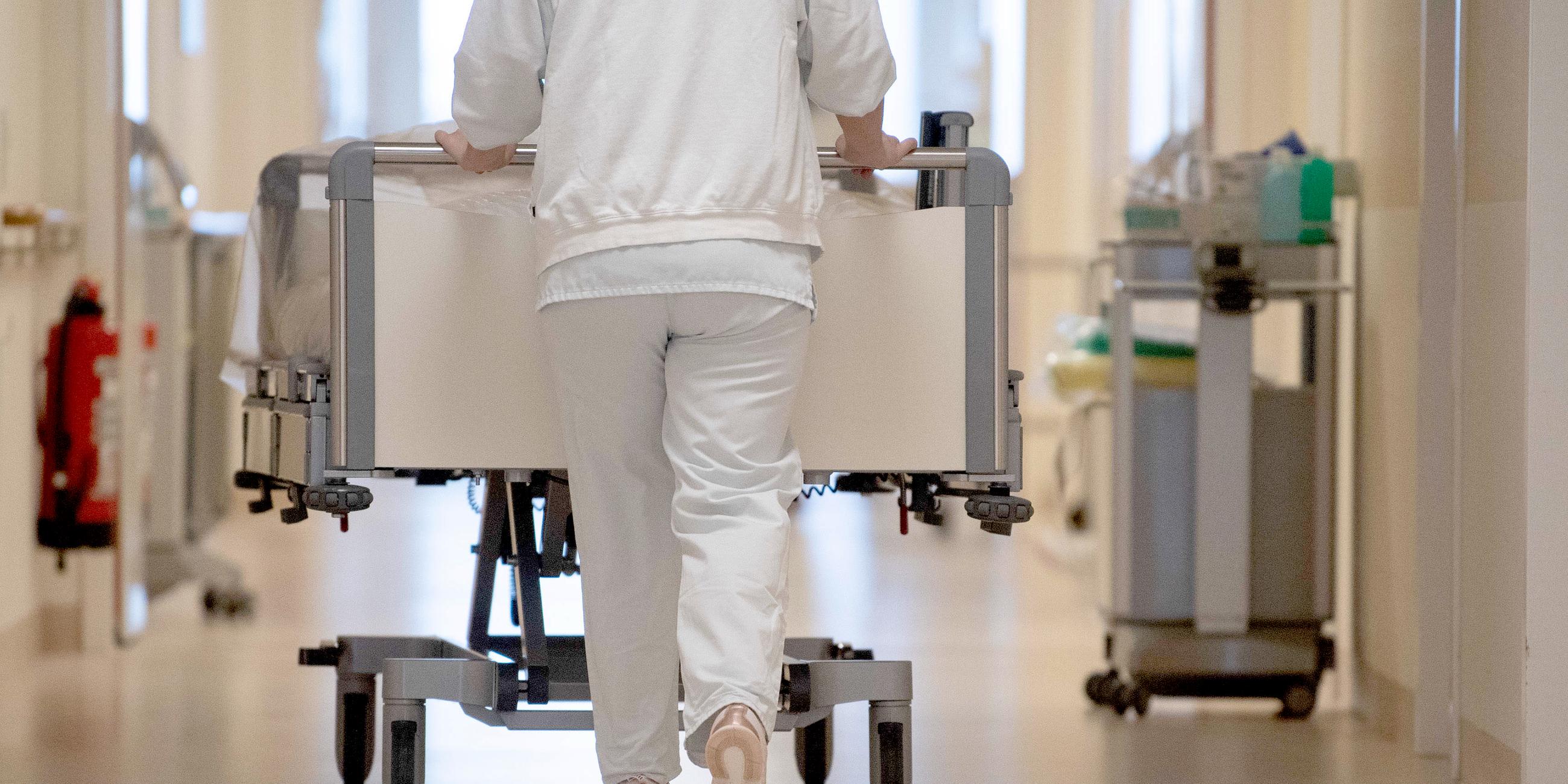 krankenpflegerin schiebt krankenbett durch einen flur