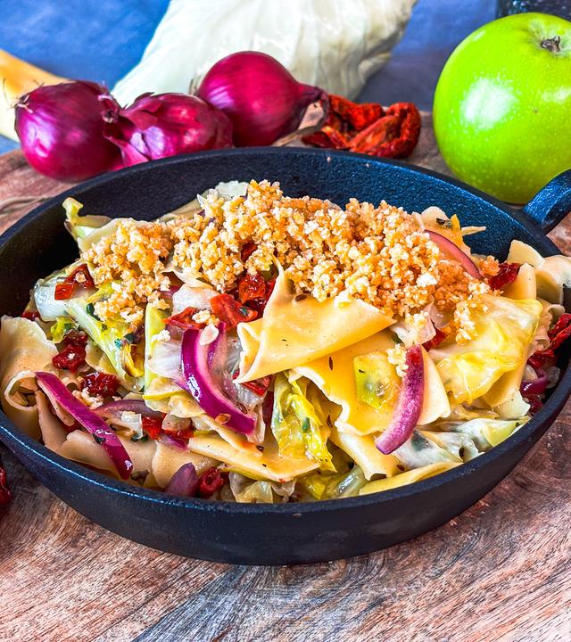 Nudeln mit Spitzkohl in einer Pfanne serviert.