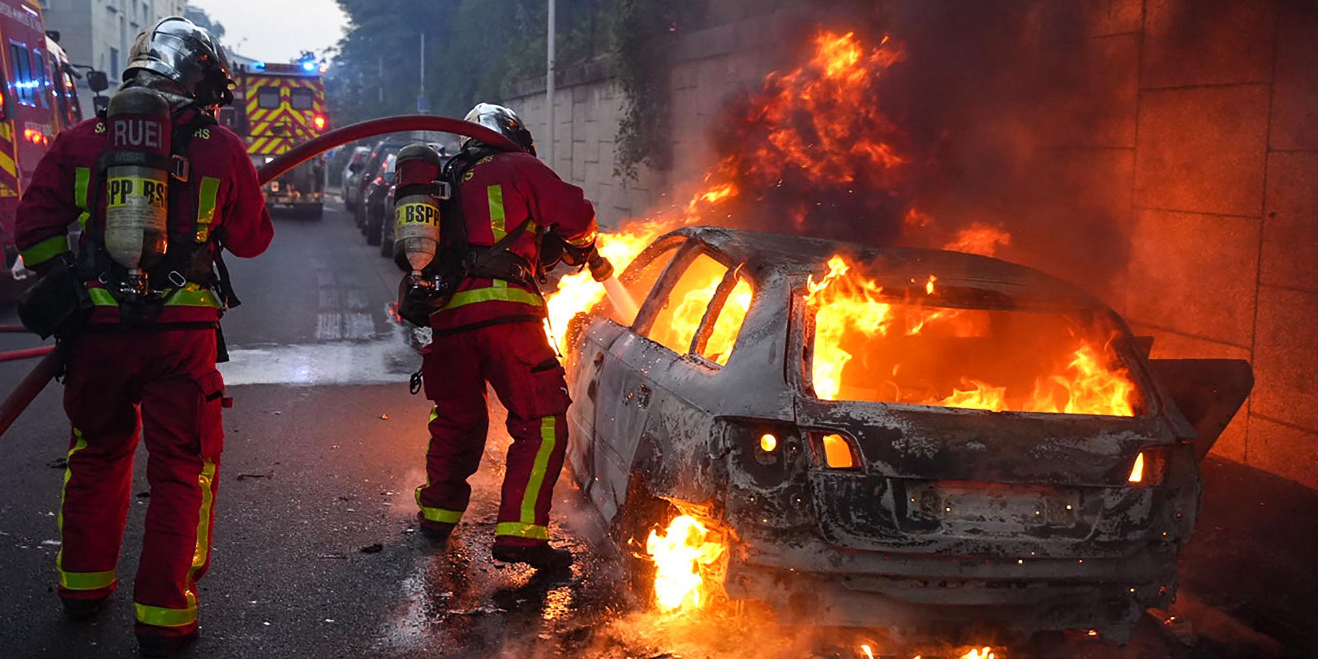 Die Feuerwehr löscht bei den Krawallen in Nanterre ein brennendes Auto.