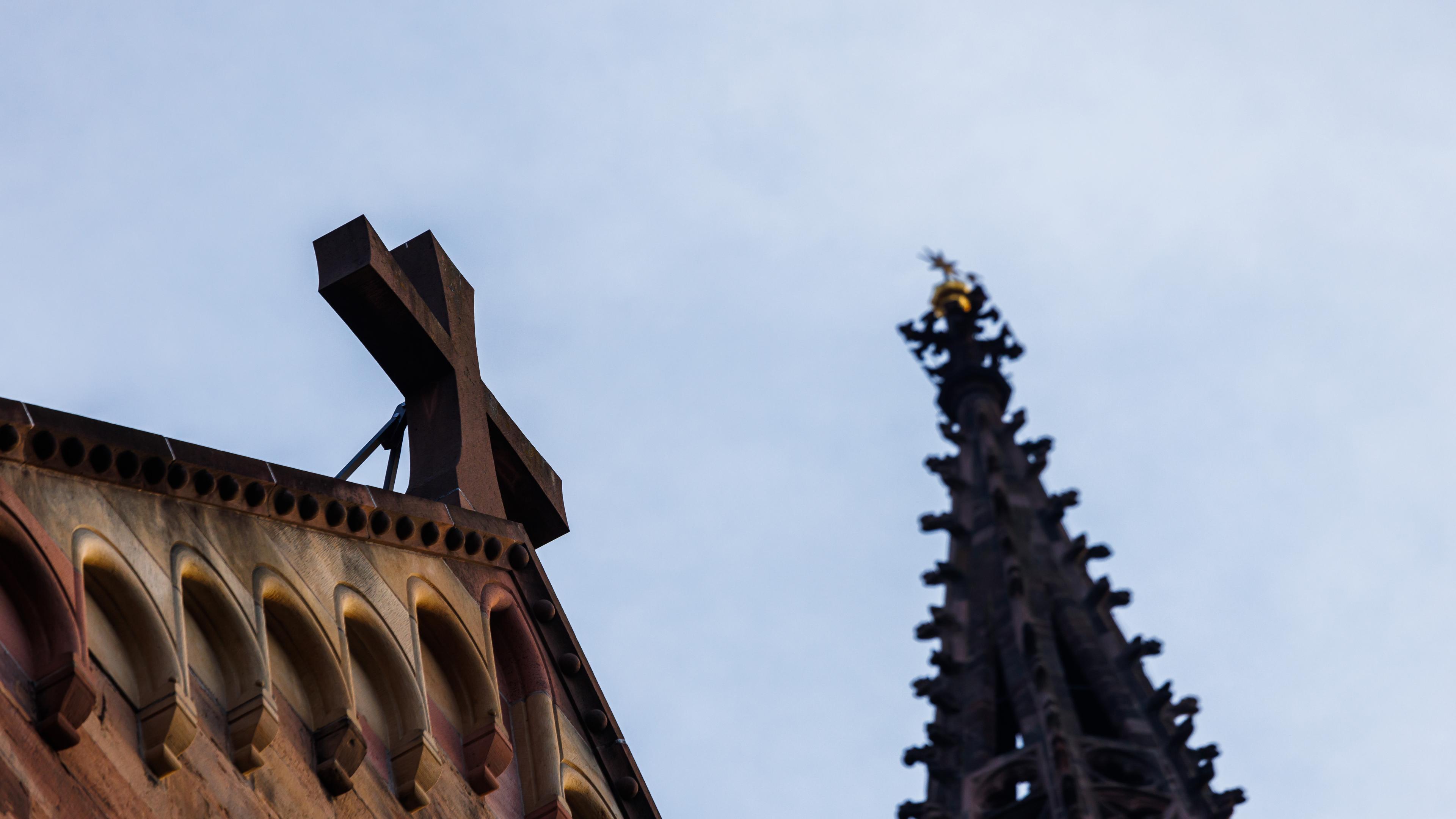 Baden-Württemberg, Freiburg im Breisgau: Ein Kreuz ist an der Fassade des Freiburger Münsters zu sehen, dahinter ein Turm des Münsters.