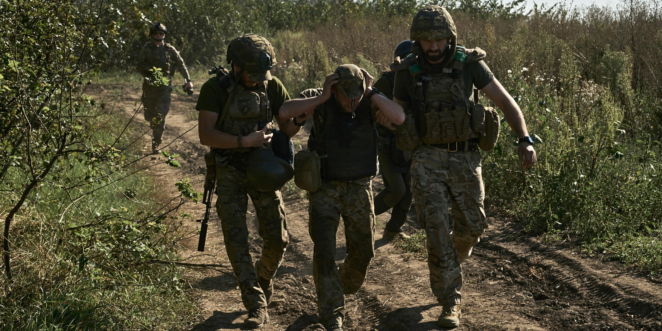 Ukrainische Soldaten helfen bei der Evakuierung eines verwundeten Soldaten an der Frontlinie in der Nähe von Bachmut in der Region Donezk, aufgenommen am 30.08.2023