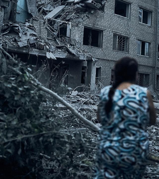 Eine ukrainische Frau geht inmitten der Trümmer eines Wohnhauses nach nächtlichem Beschuss in Mykolaiv (Ukraine), aufgenommen am 02.08.2022