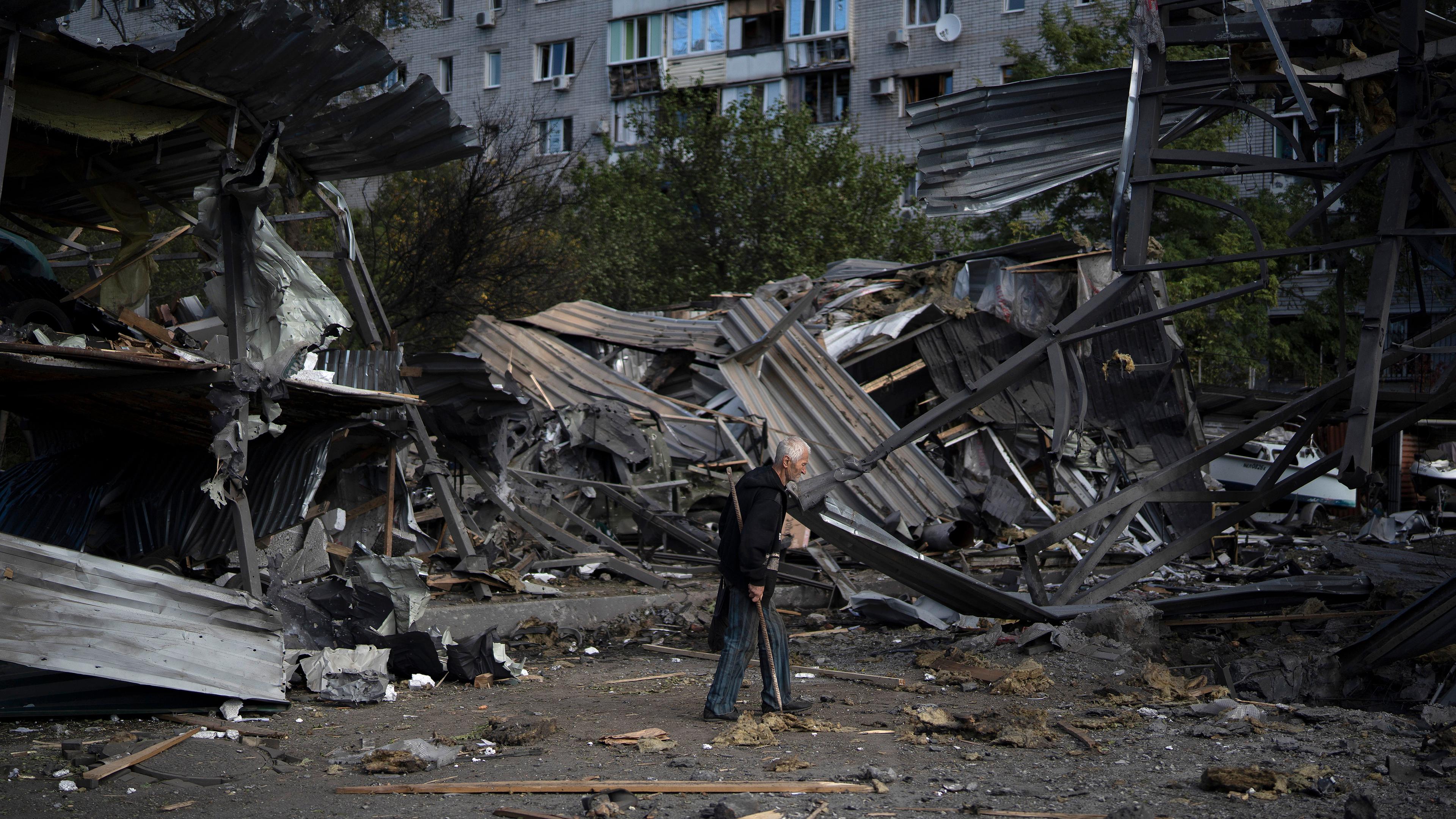 Ein älterer Mann geht an einer Autowerkstatt vorbei, die nach einem russischen Angriff in Saporischschja zerstört wurde (Ukraine), aufgenommen am 11.10.2022
