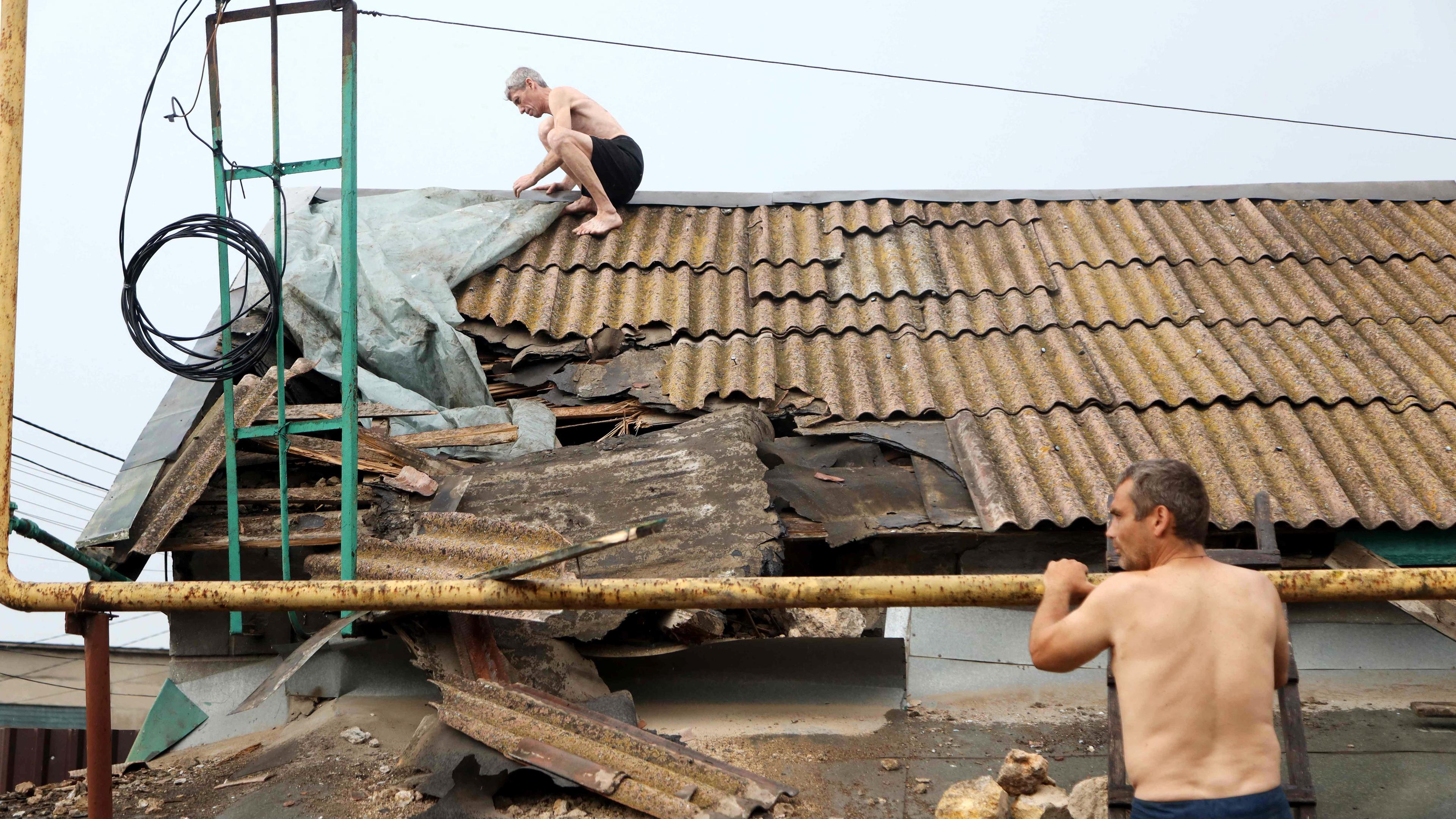 Ein Mann repariert das Dach eines Hauses, das durch eine russische Rakete beschädigt wurde, aufgenommen am 18.07.2023