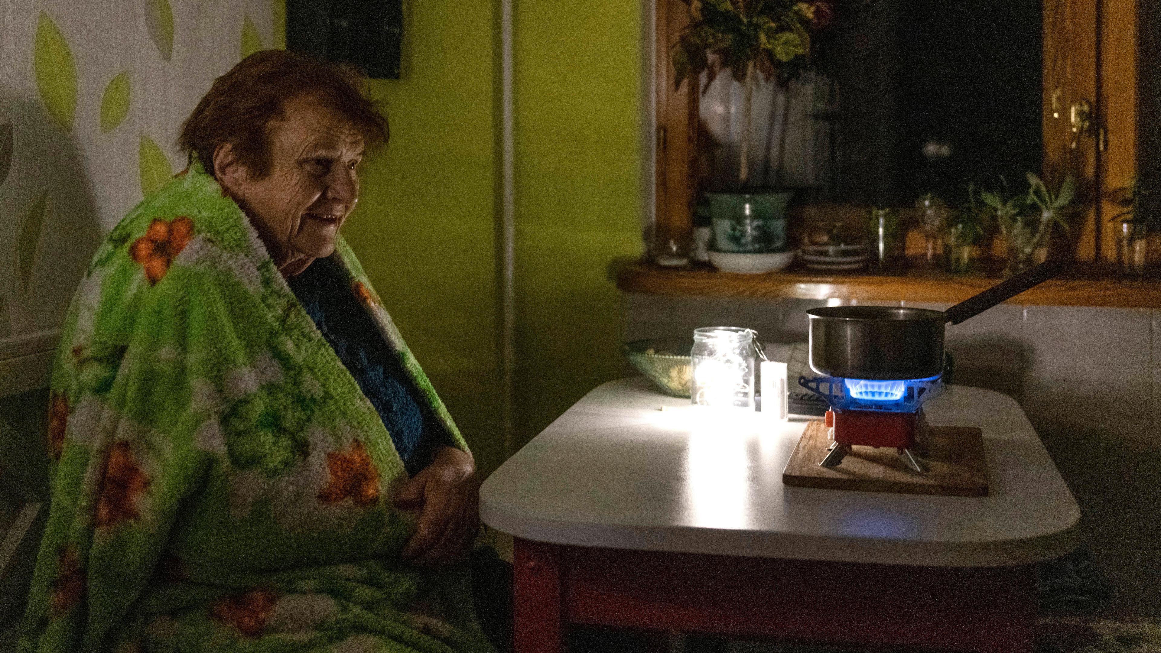Eine ältere Frau kocht während eines Stromausfalls Essen auf einem Gasbrenner, aufgenommen am 14.11.2022 in Kiew (Ukraine)
