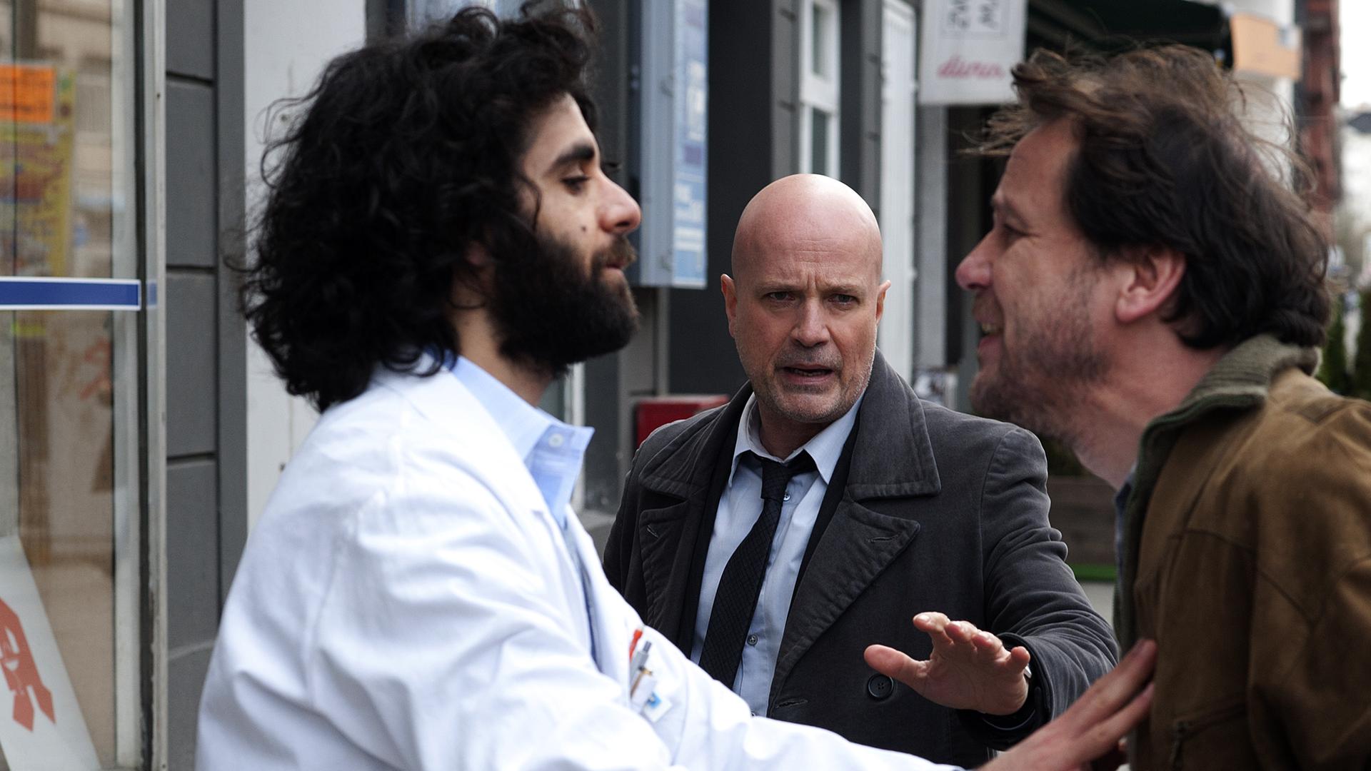 Schumann (Christian Berkel) will einen Streit schlichten und stellt sich zwischen beide Männer