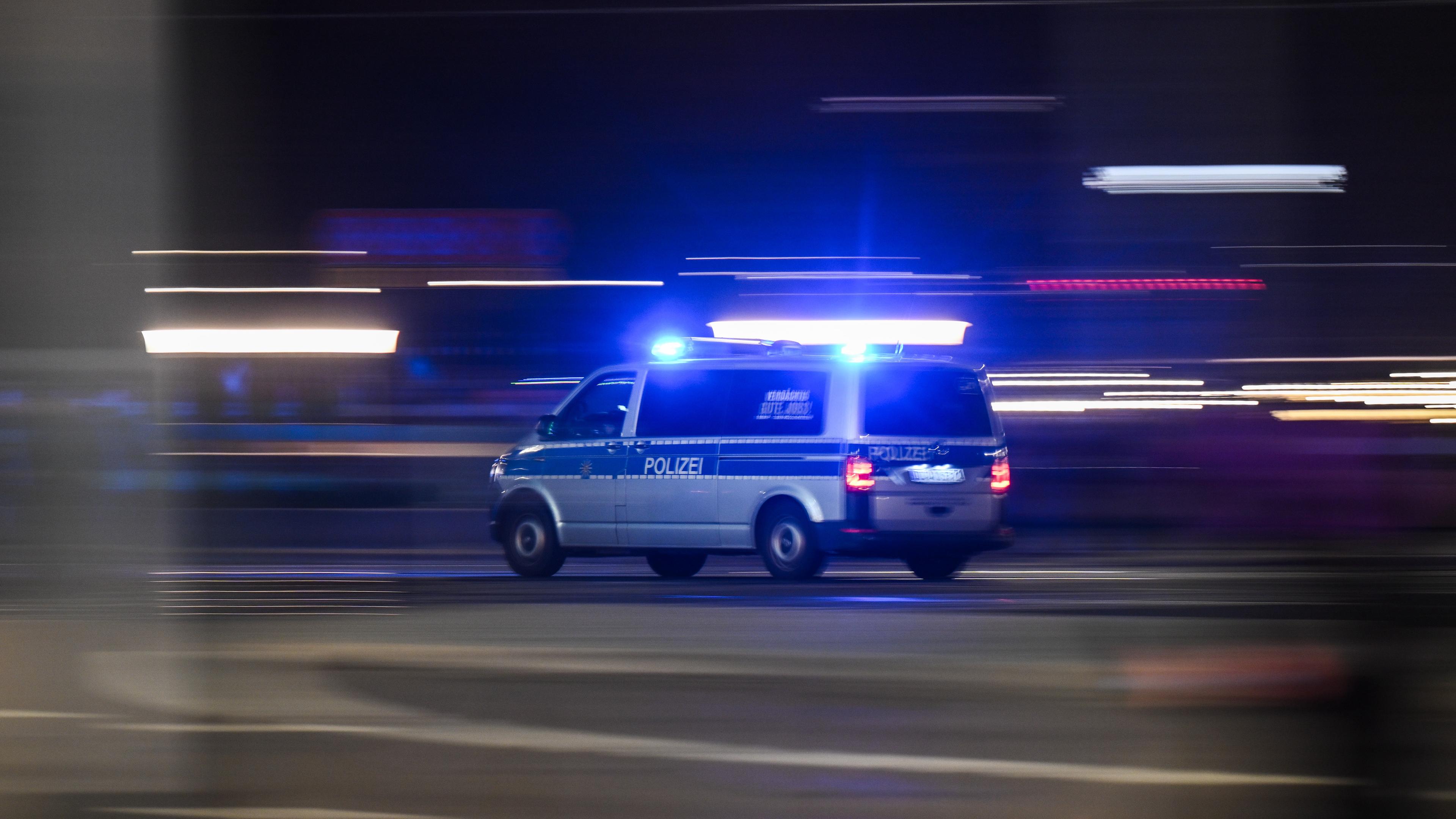 Ein Polizewagen fährt mit Blaulicht auf einer Straße.