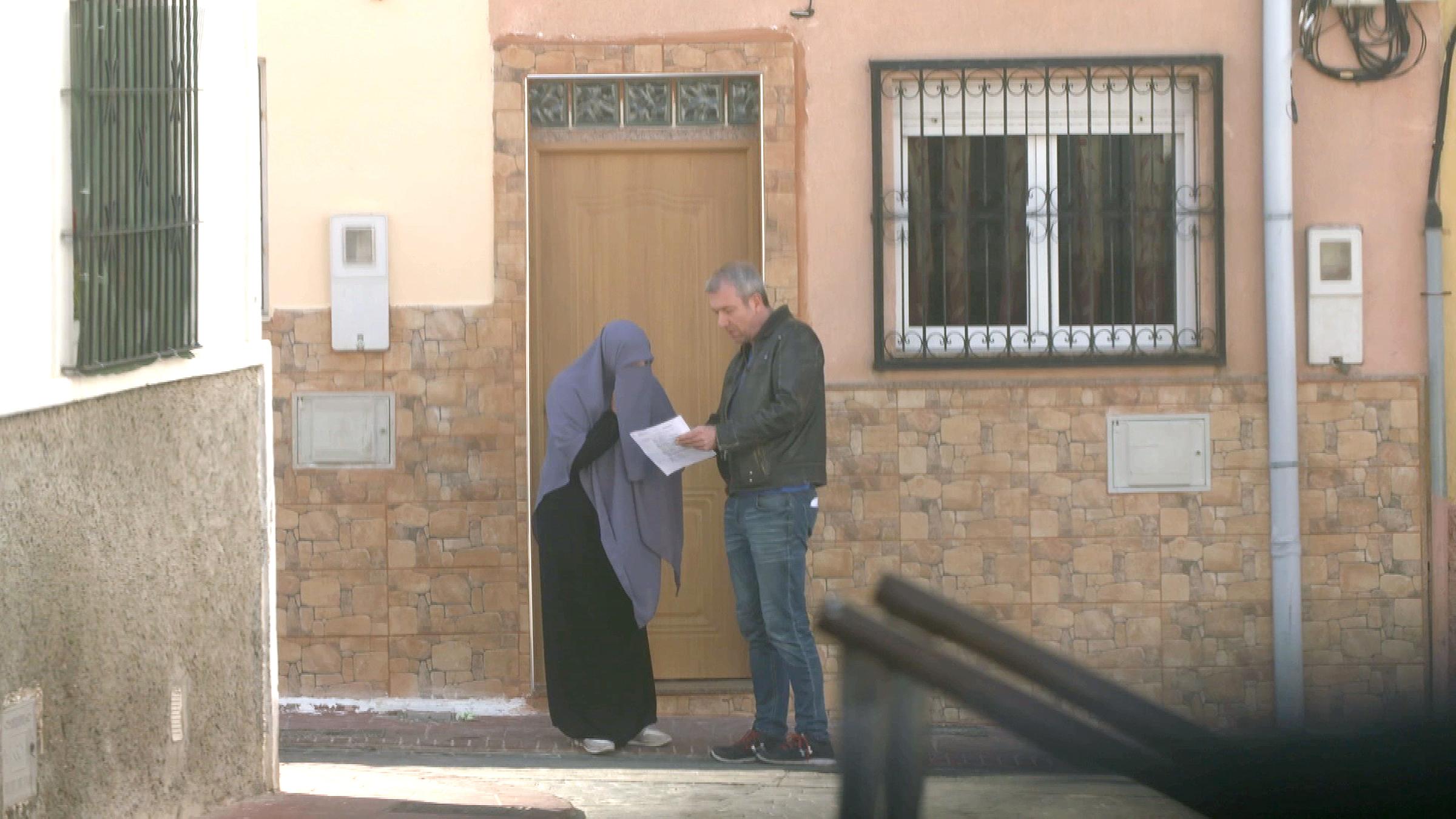 Die verschleierte Laila M. und "Frontal 21"-Autor Hans Koberstein unterhalten sich vor einem Gebäude. Koberstein zeigt Laila M. ein Papier, das er in der Hand hält.