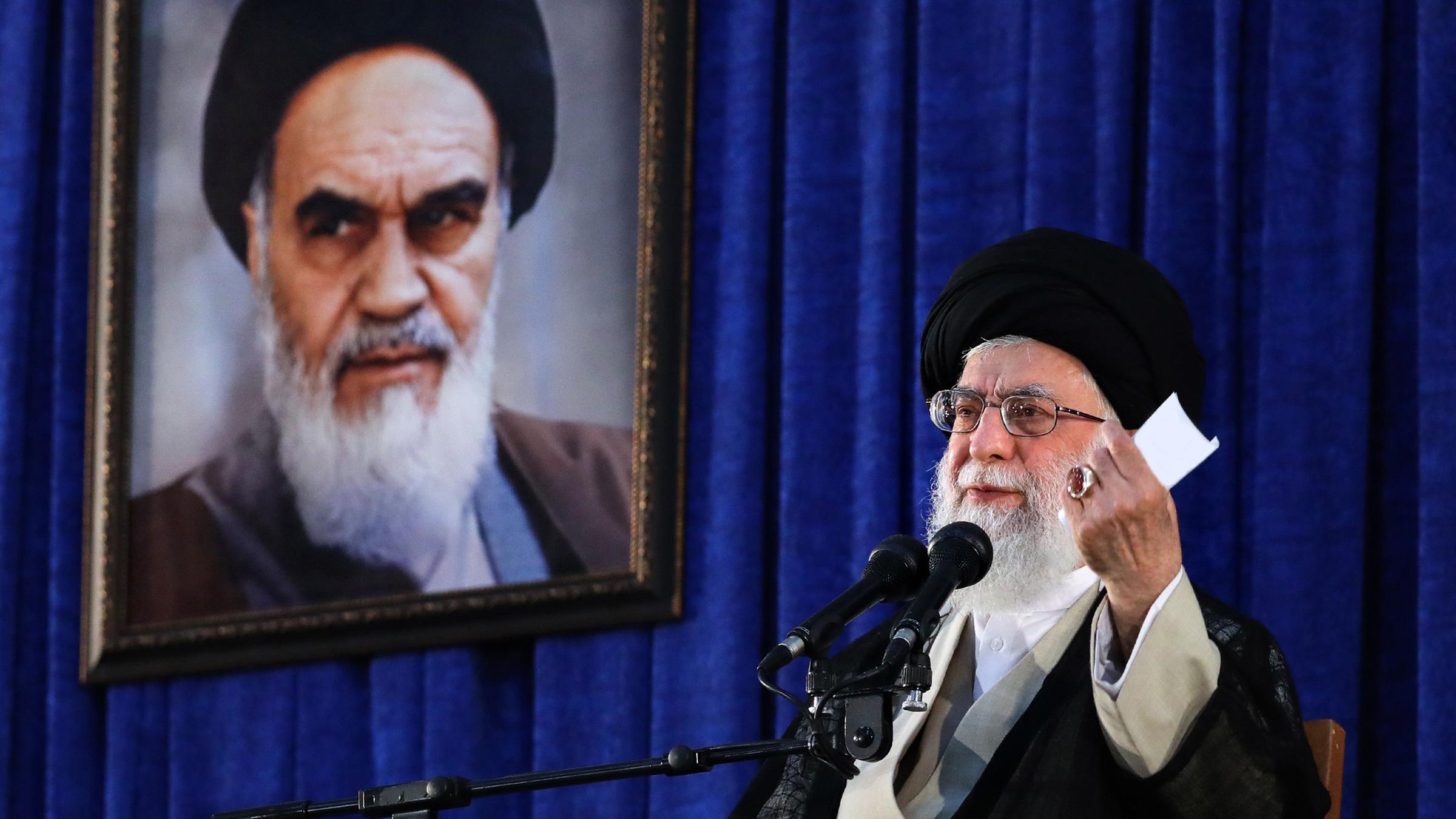 "Krisenherd Iran – Gottesstaat zwischen Macht und Ohnmacht": Ajatollah Ali Chamenei spricht in ein Mikrofon vor einem blauen Vorhang.