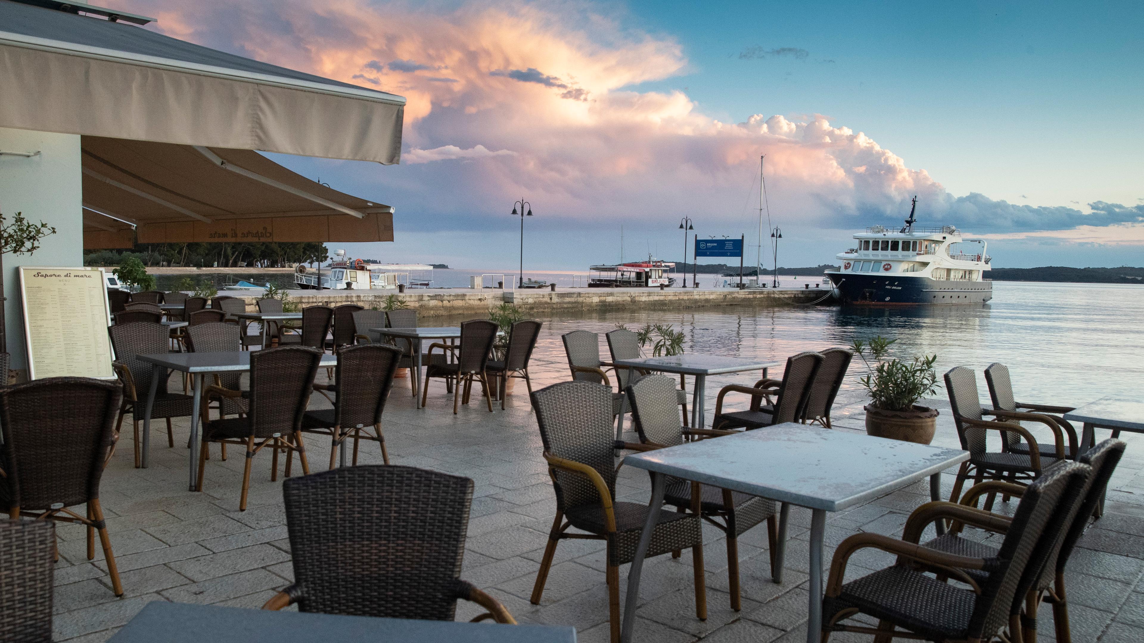 Kroatien, Fazana: Die Tische in den Cafés und Restaurants im Hafen von Fazana sind nicht besetzt. Archivbild