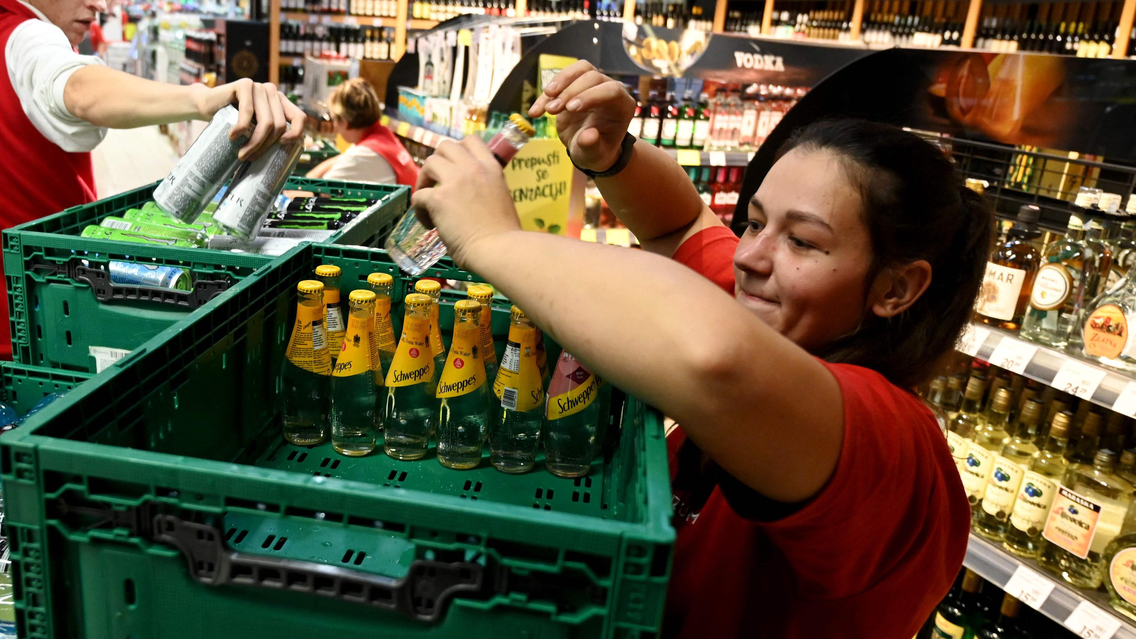 Eine Angestellte nimmt in einem Supermarkt in Zagreb, Kroatien Getränke-Produkte aus den Regalen.