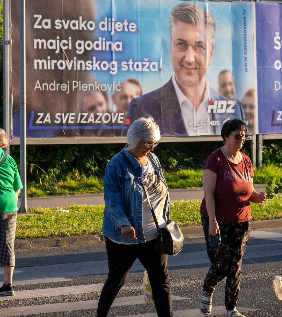 Fußgänger überqueren eine Straße vor Wahlplakaten in Zagreb, Kroatien, am Sonntag, 14.04.2024