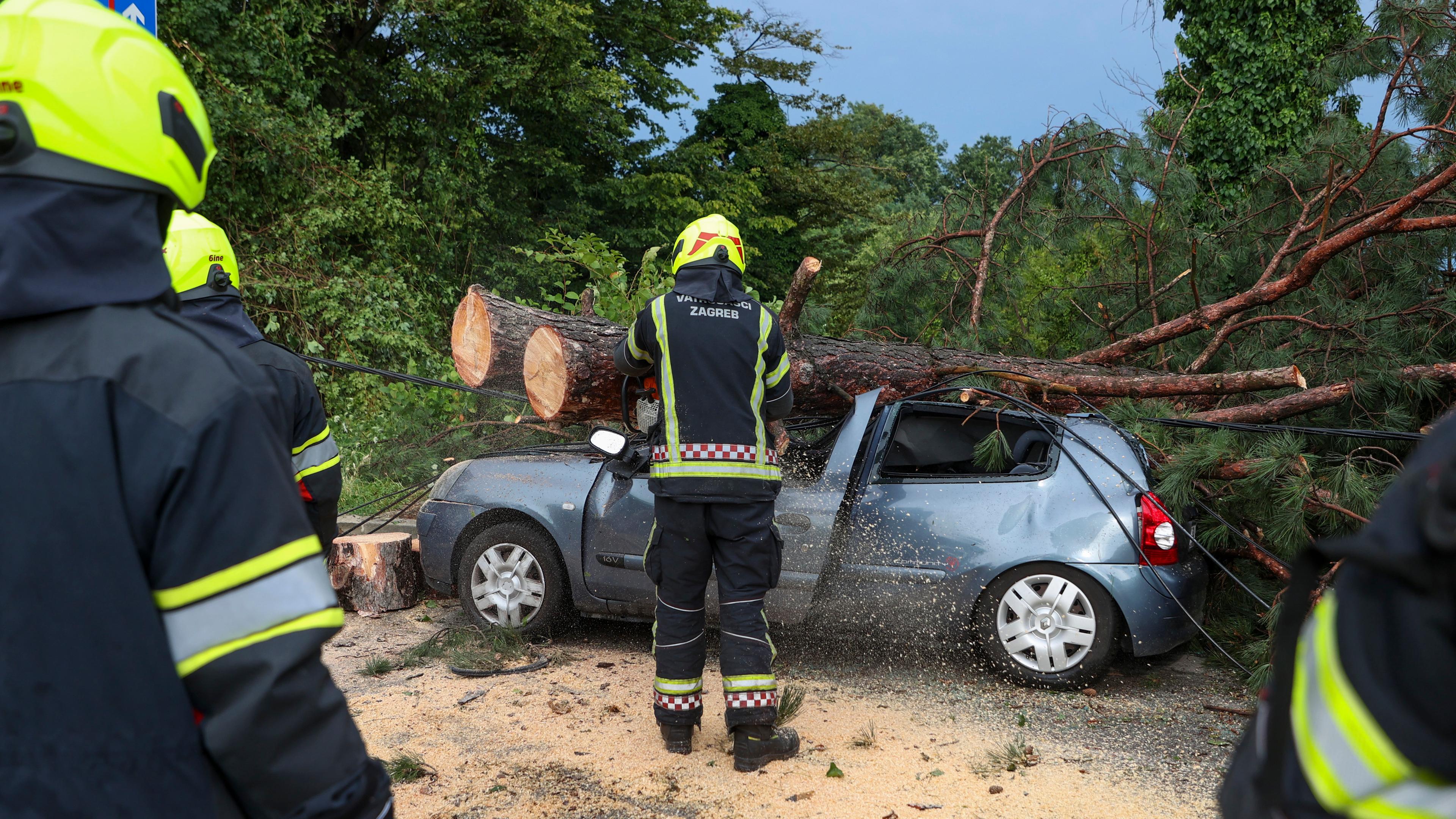 Feuerwehrleute entfernen nach einem heftigen Sturm in Zagreb, Kroatien, Äste von einem beschädigten Auto. 