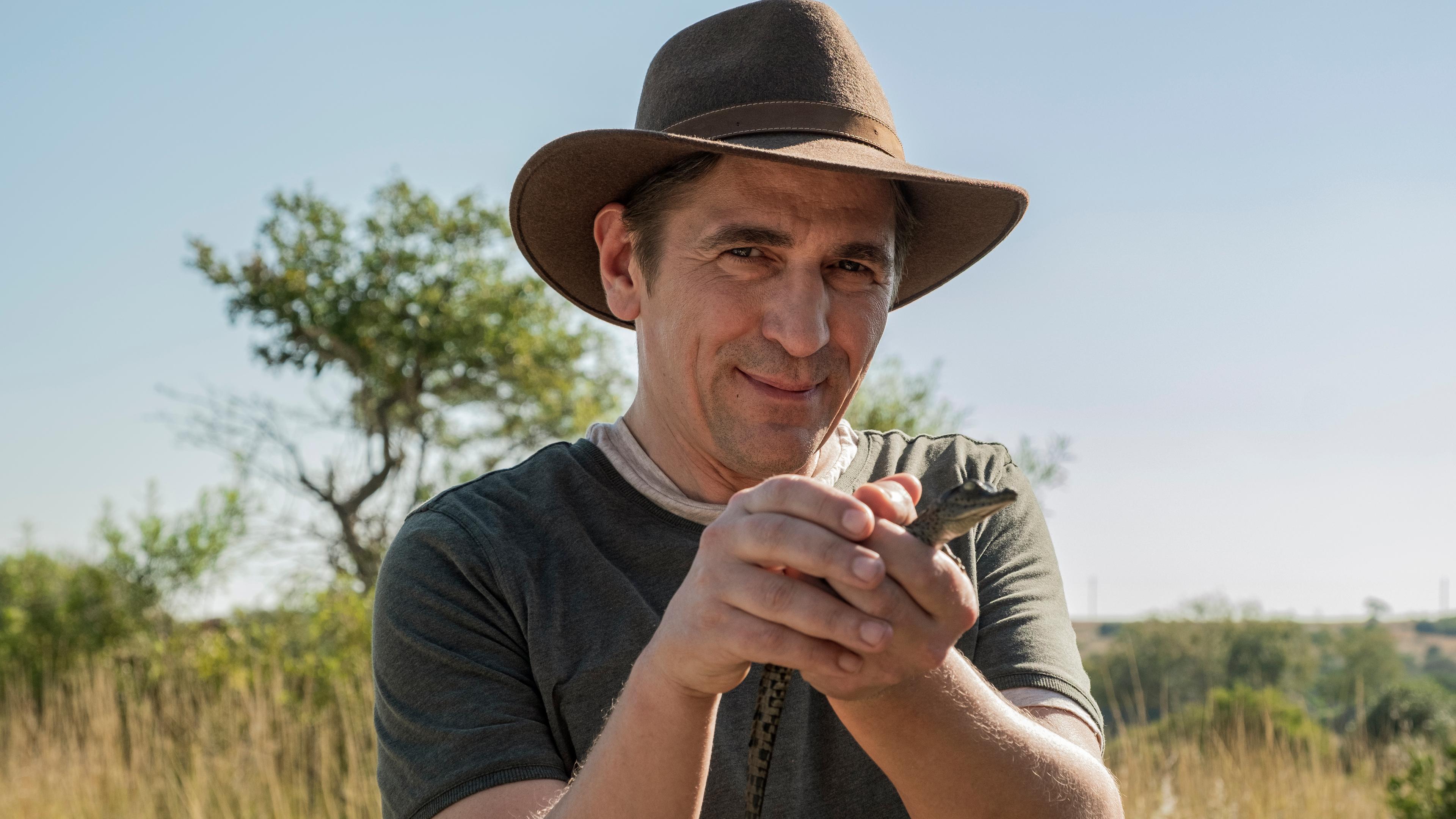 Fritz hält ein Baby-Krokodil in der Hand.