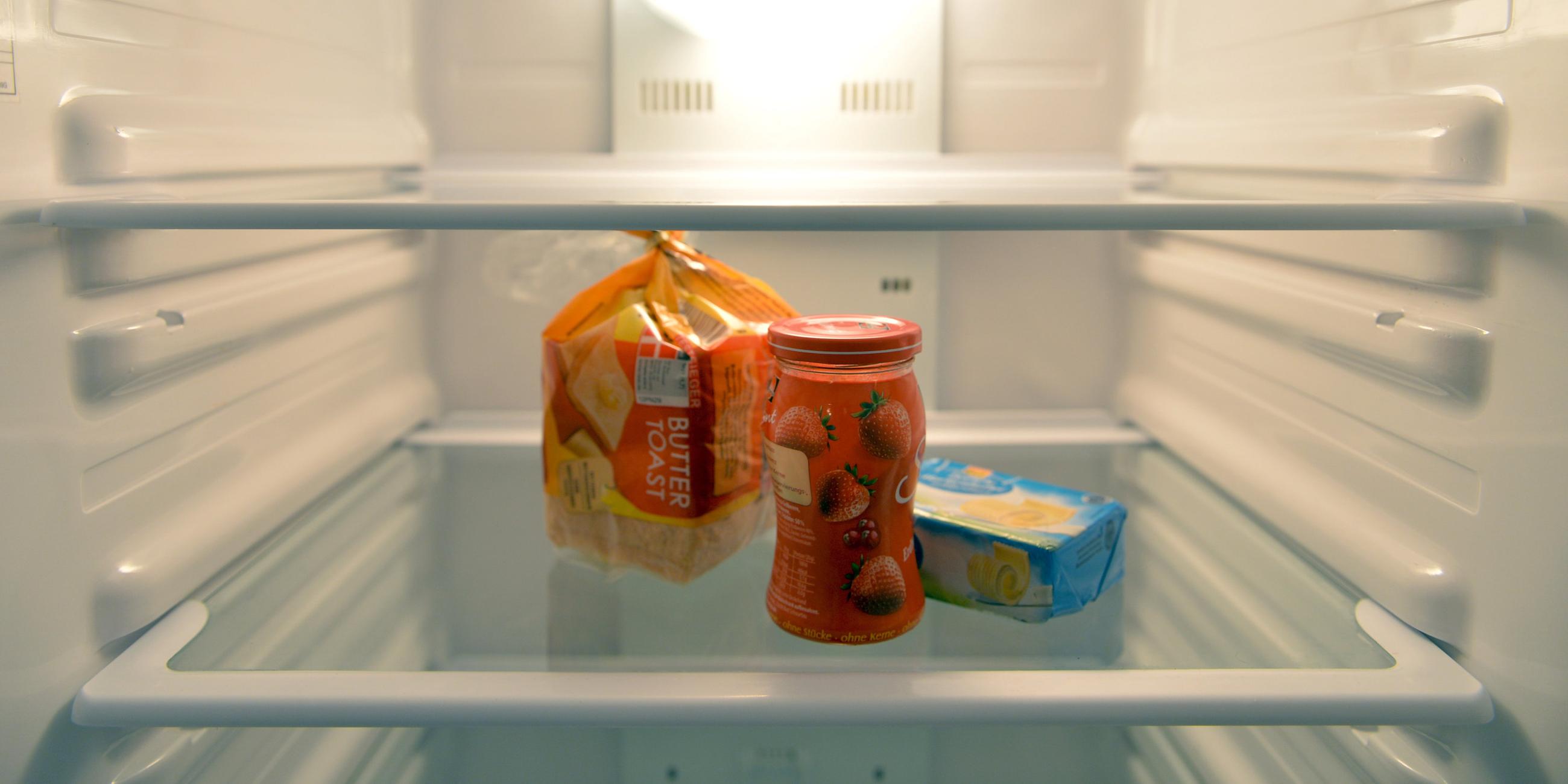 Man sieht einen fast leeren Kühlschrank, in dem nur noch etwas Toast, Marmelade und Butter steht.