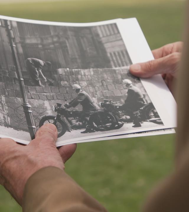 Mann hält Bild vom Bau der Berliner Mauer in der Hand