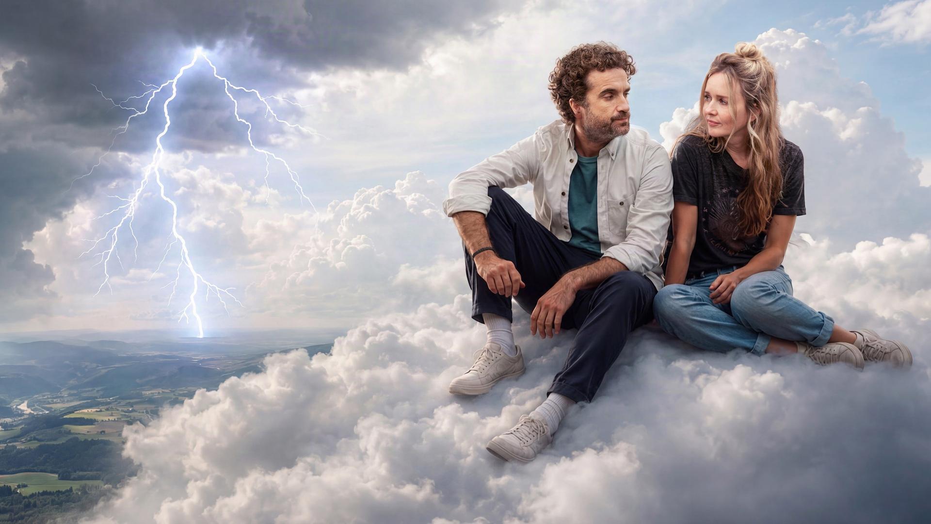Markus und Miriam Bachmann (Oliver Wnuk, Stefanie Stappenbeck) sitzen einander zugewandt auf einer Wolke. Links neben ihnen zieht ein Gewitter heran, es blitzt.