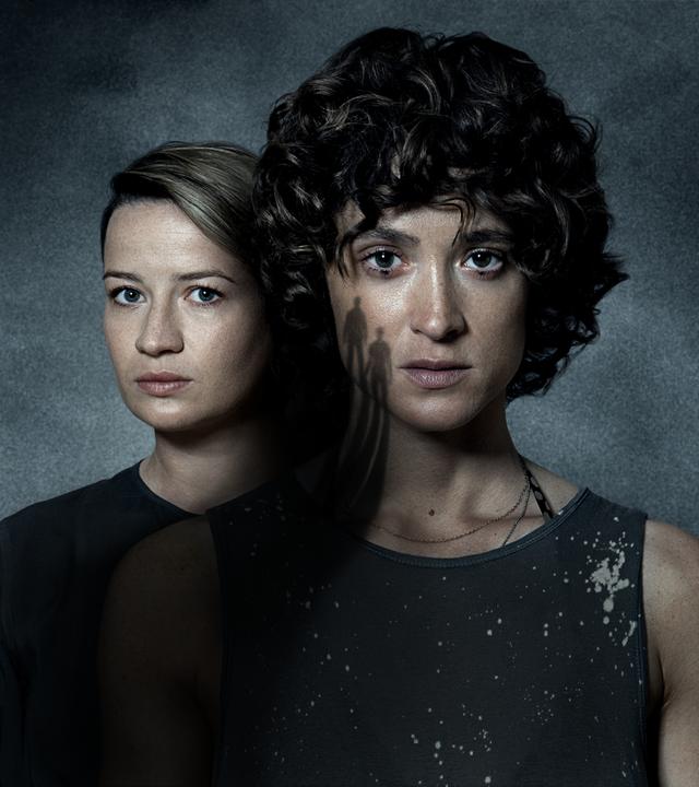 Die Schauspielerinnen Nina Gummich und Friederike Beckt stehen halb versetzt hintereinander und blicken ernst in die Kamera.