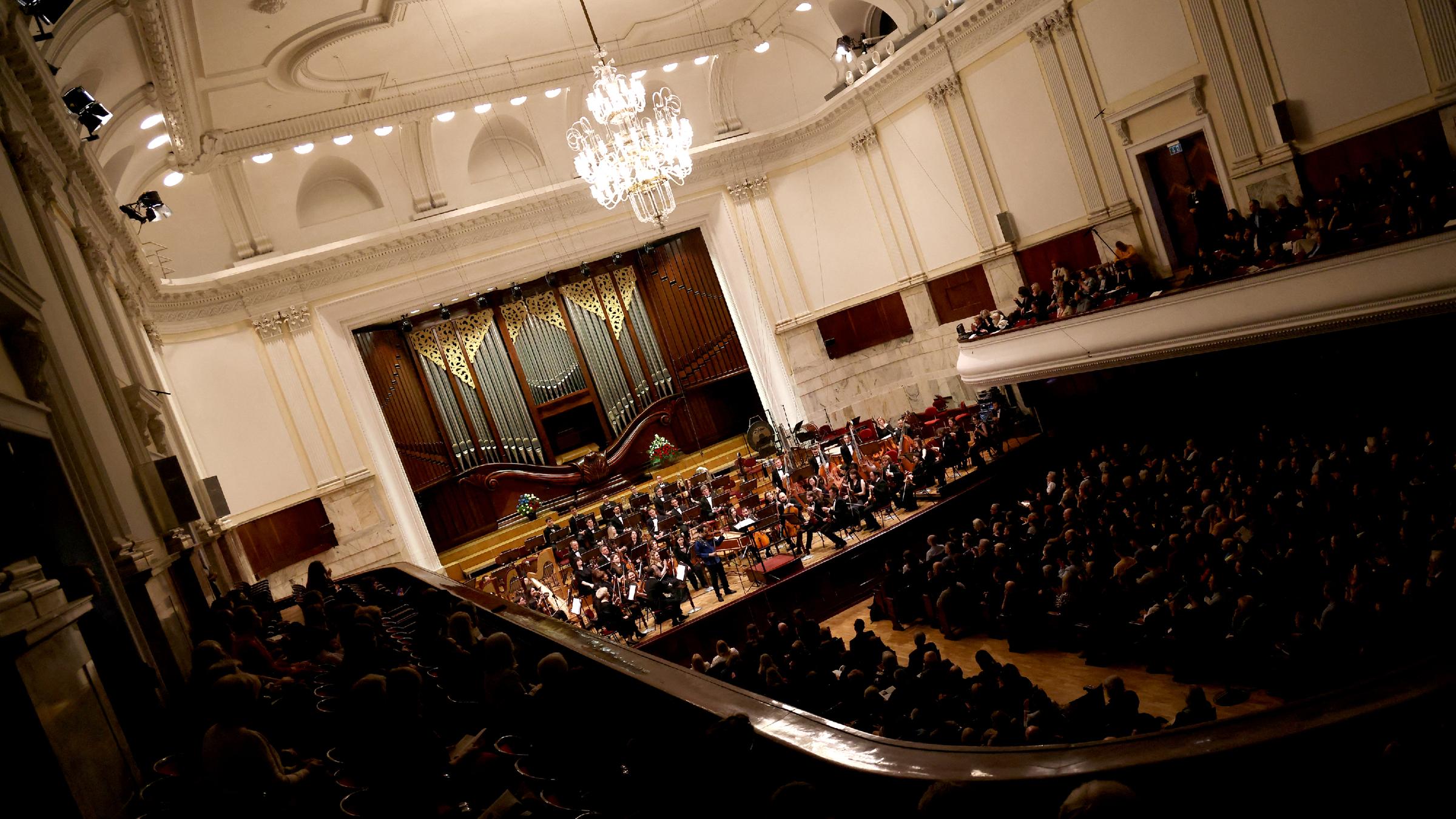 Ein Konzertsaal, auf dessen Bühne ein Orchester steht und Musik macht.