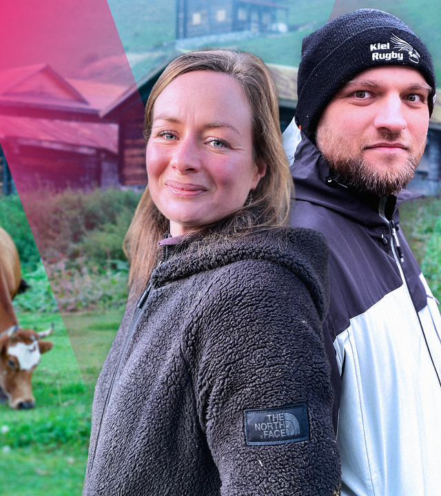 Eine junge Frau und ein junger Mann, im Hintergrund ein Almbauernhof und eine Kuh auf der Weide