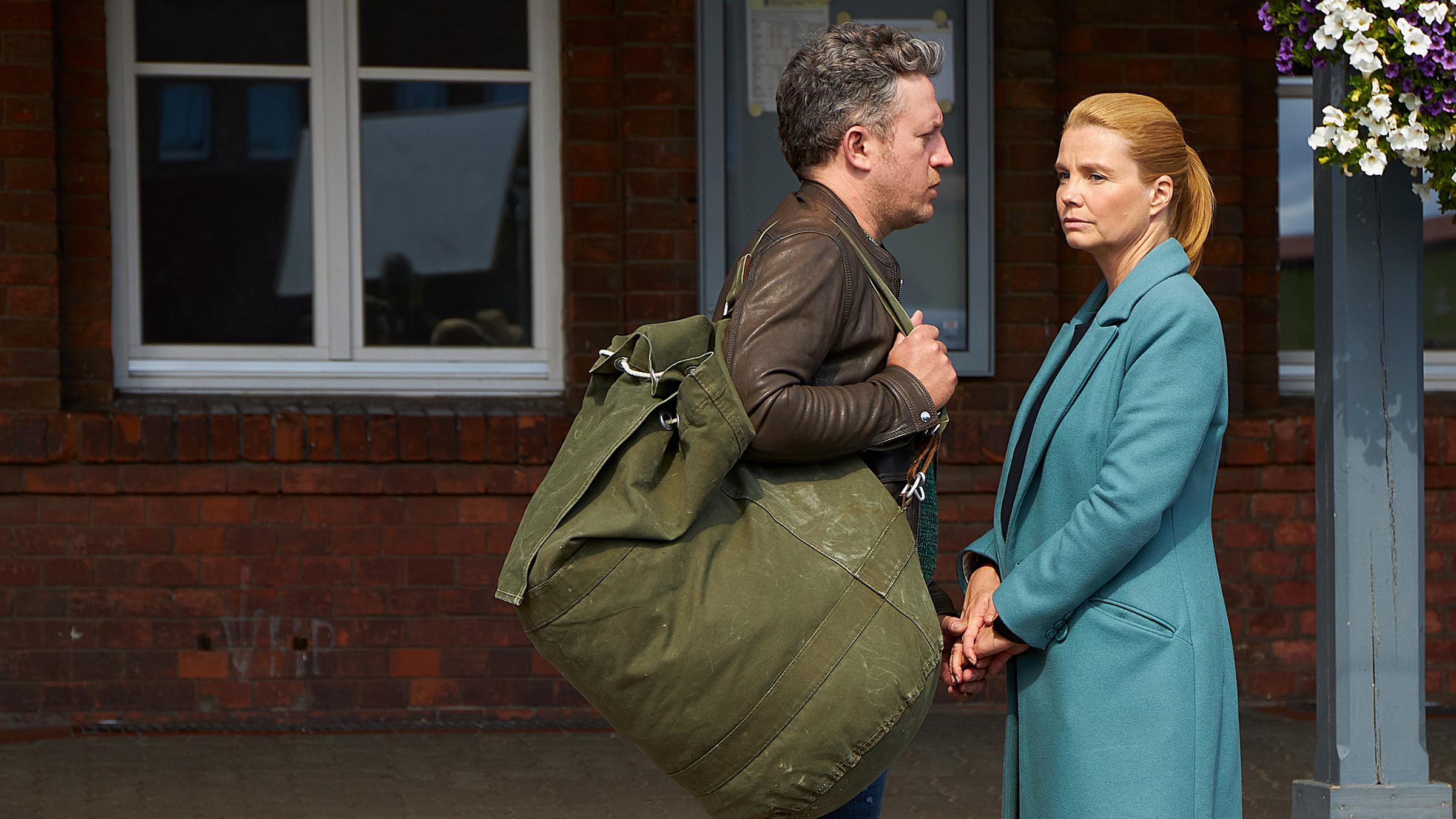 Ella (Annette Frier) und Jannis (Josef Heynert) stehen sich auf einem Bahnsteig gegenüber. Er trägt schweres Reisegepäck.