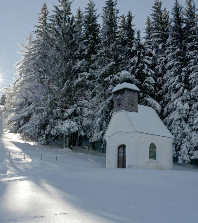 Kleine Kapelle in verschneiter Landschaft am Waldrand