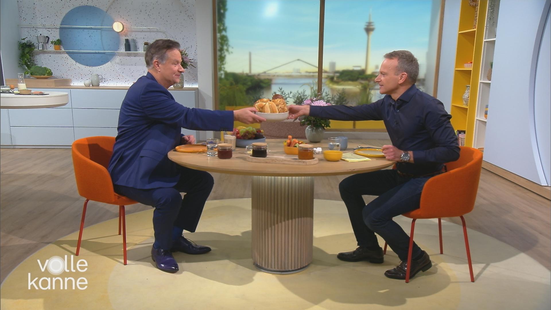 Lars Reichow und Carsten Rüger sitzen am Volle-Kanne-Frühstückstisch und reichen sich den Brotkorb rüber