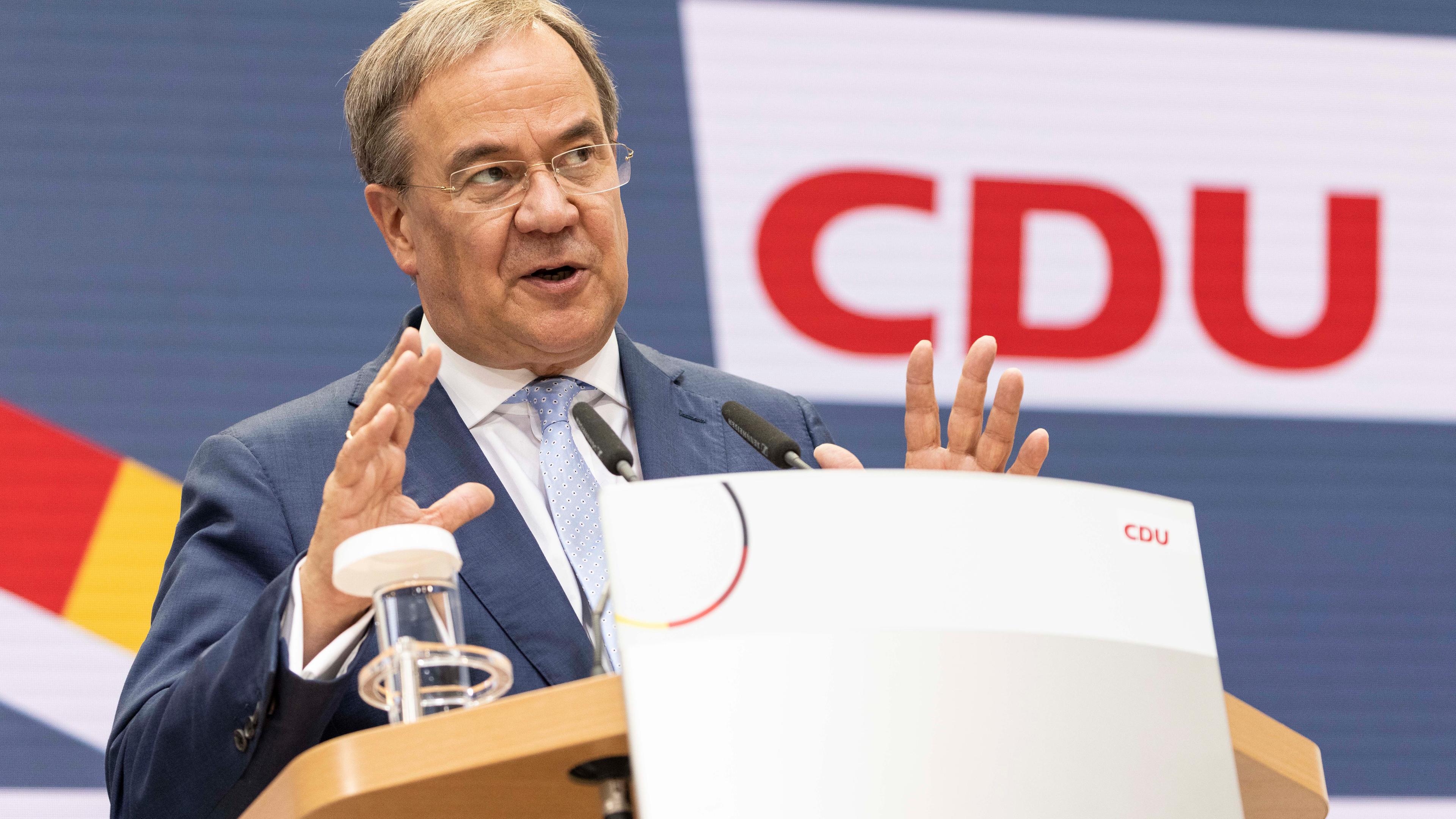 CDU-Kanzlerkandidat Armin Laschet steht an einem Rednerpult und hat gestikulierend die Hände erhoben.
