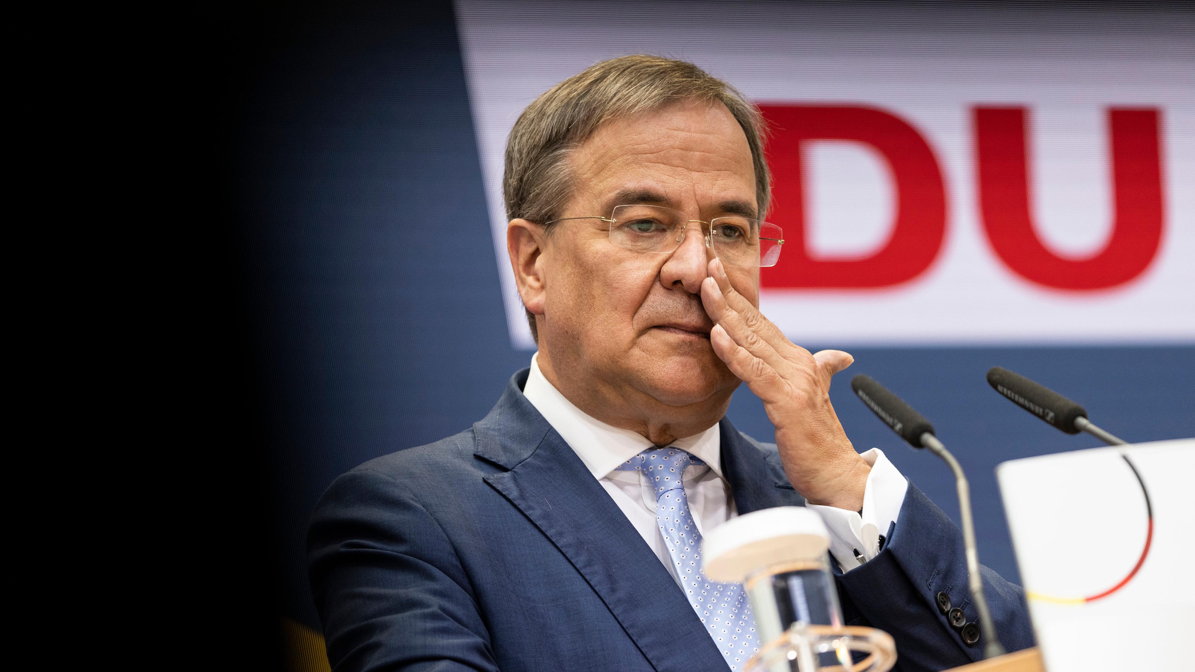 CDU-Chef Armin Laschet fasst sich am Rednerpult an die Nase.