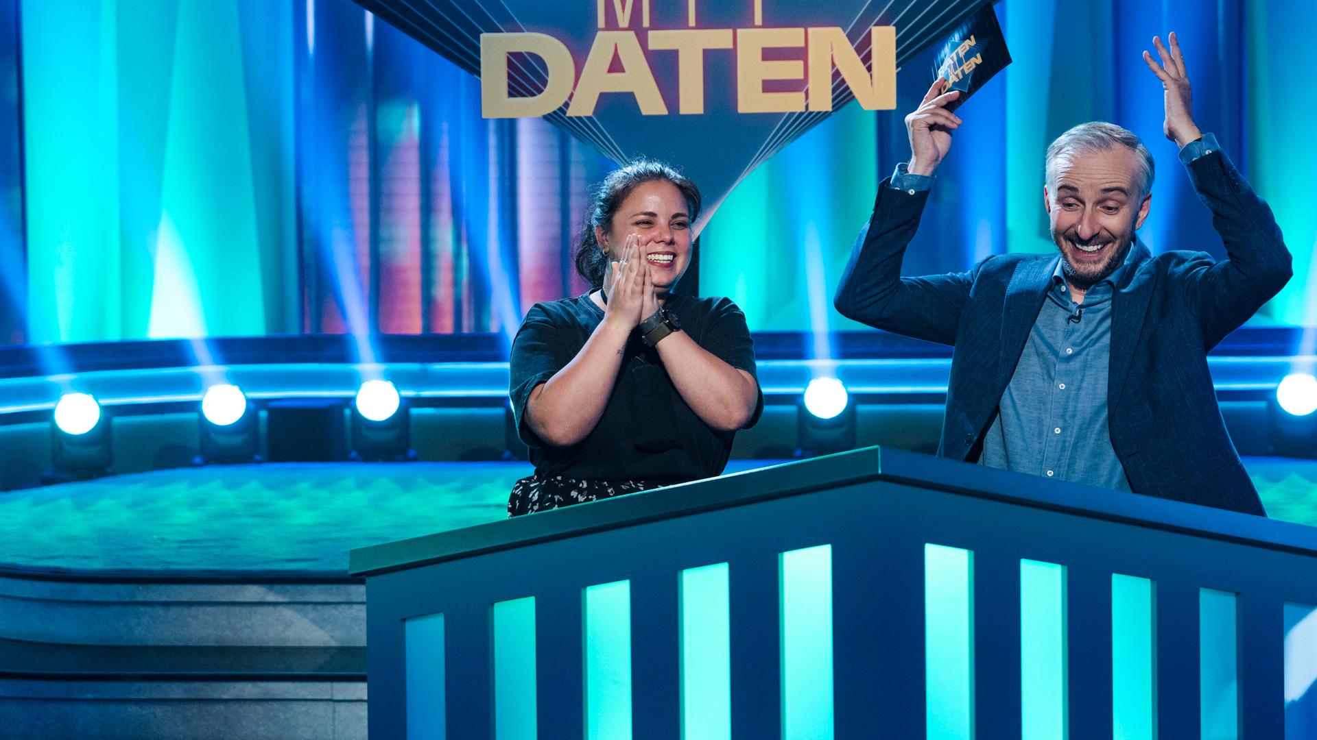 Moderator Jan Böhmermann in der ZDF Prime Time Sendung "Lass dich überwachen!" gemeinsam mit Kandidatin Samantha aus Bergisch Gladbach in der Rubrik Raten mit Daten. Jan Böhmermann jubelt und hat die Arme in der Luft.