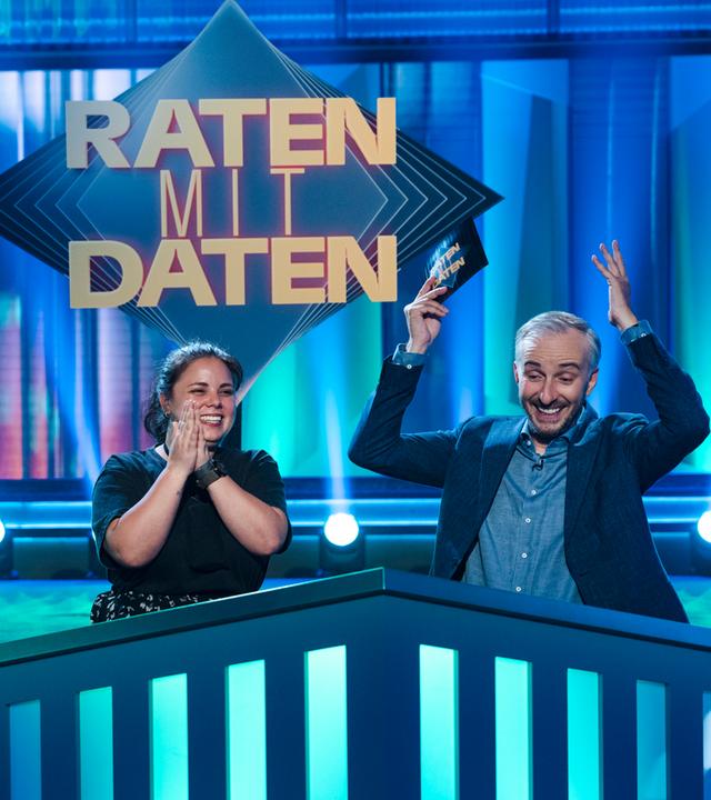 Moderator Jan Böhmermann in der ZDF Prime Time Sendung "Lass dich überwachen!" gemeinsam mit Kandidatin Samantha aus Bergisch Gladbach in der Rubrik Raten mit Daten. Jan Böhmermann jubelt und hat die Arme in der Luft.