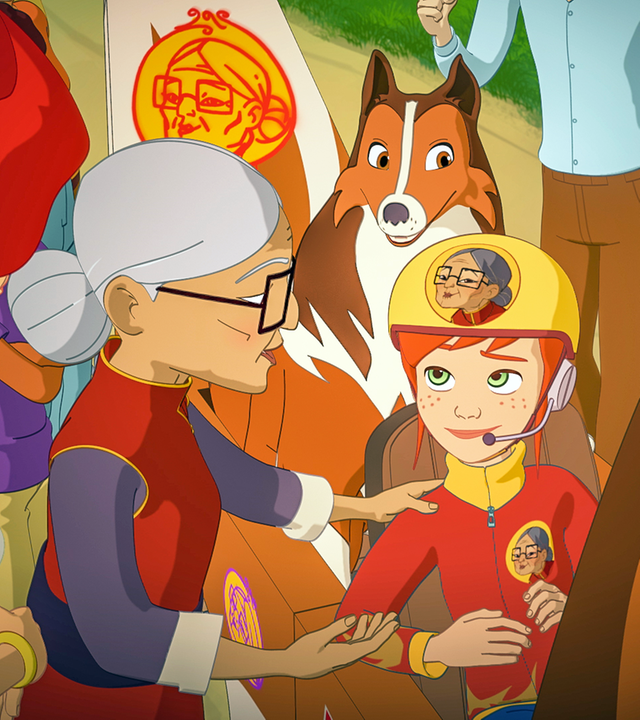 Hinter der Zieleinfahrt sitzen Zoé und Lassie in ihrer Seifenkiste. Mrs. Lee steht neben Zoé und fasst sie an der Schulter an. Die beiden sind von weiteren Menschen umringt.