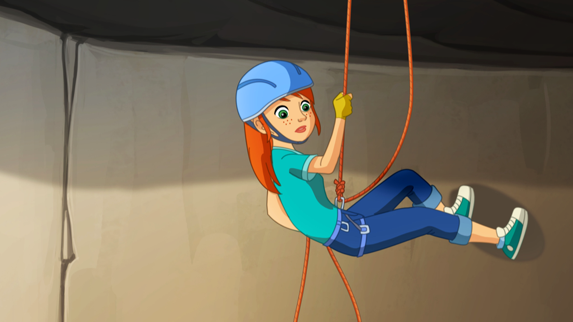 Zoé hängt in einer Felswand in den Seilen und blickt nach unten.