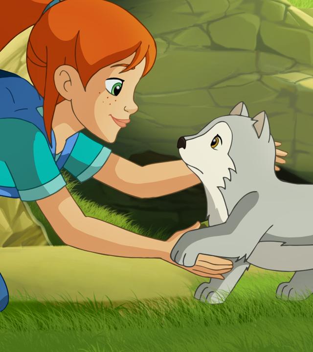 Zoé kniet auf einer Wiese, während ein kleiner Wolf traurig auf sie zu läuft. Sie lächelt und streckt ihre Arme nach ihm aus. 