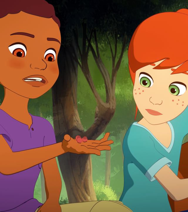 Harvey und Zoé sitzen vor einem Waldgebiet. Lassie steht neben Zoé. Alle drei schauen auf Harveys ausgestreckte Hand, in der rote Samen liegen. 