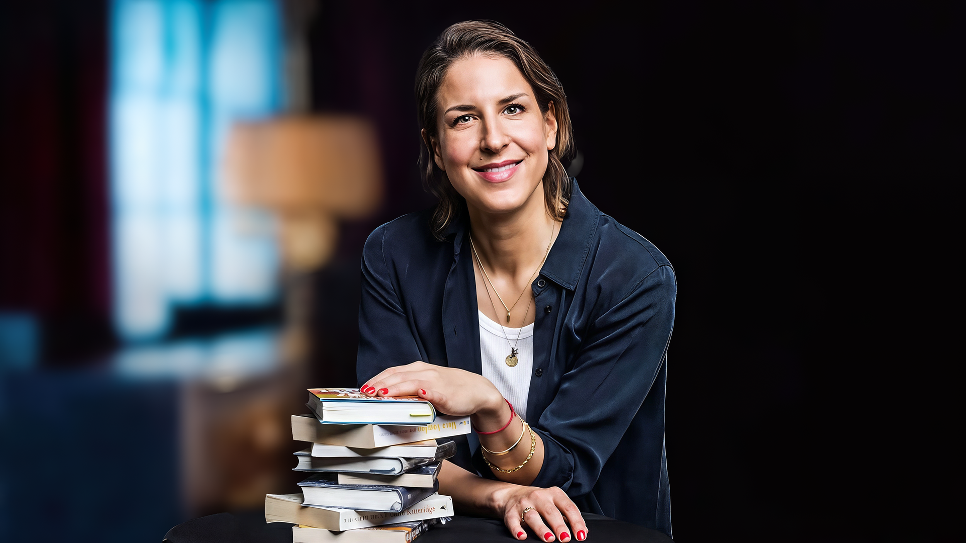 Lächelnde Frau legt eine Hand auf einen Bücherstapel