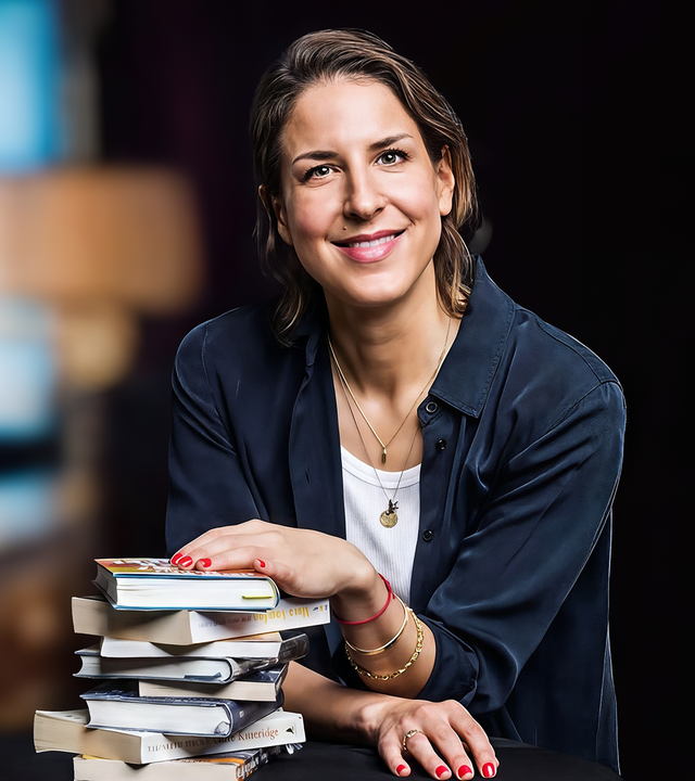 Lächelnde Frau legt eine Hand auf einen Bücherstapel