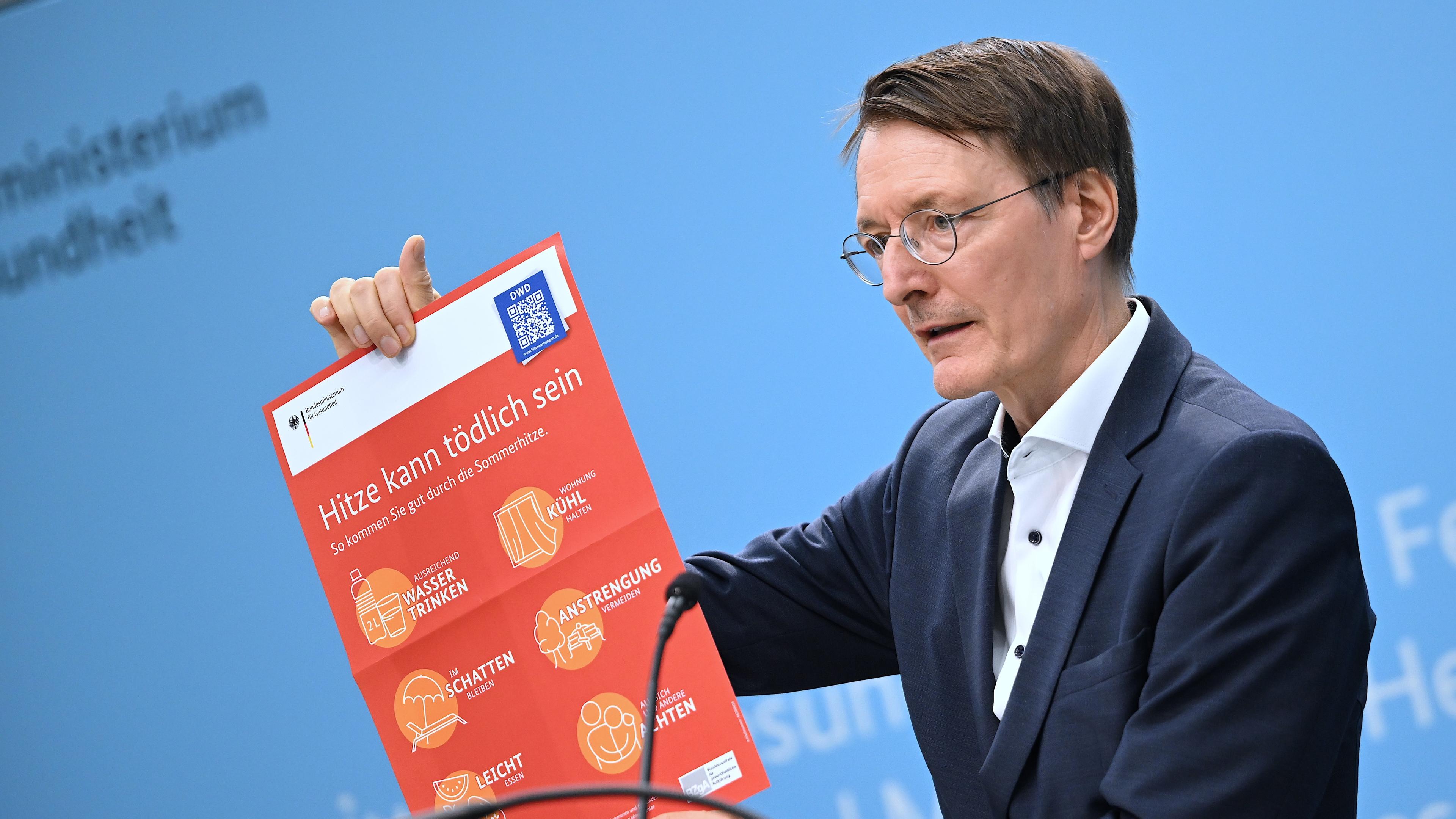 Bundesgesundheitsminister Karl Lauterbach (SPD) hält ein Plakat mit der Aufschrift «Hitze kann tödlich sein» während einer Pressekonferenz zum Thema Hitzeschutz. 