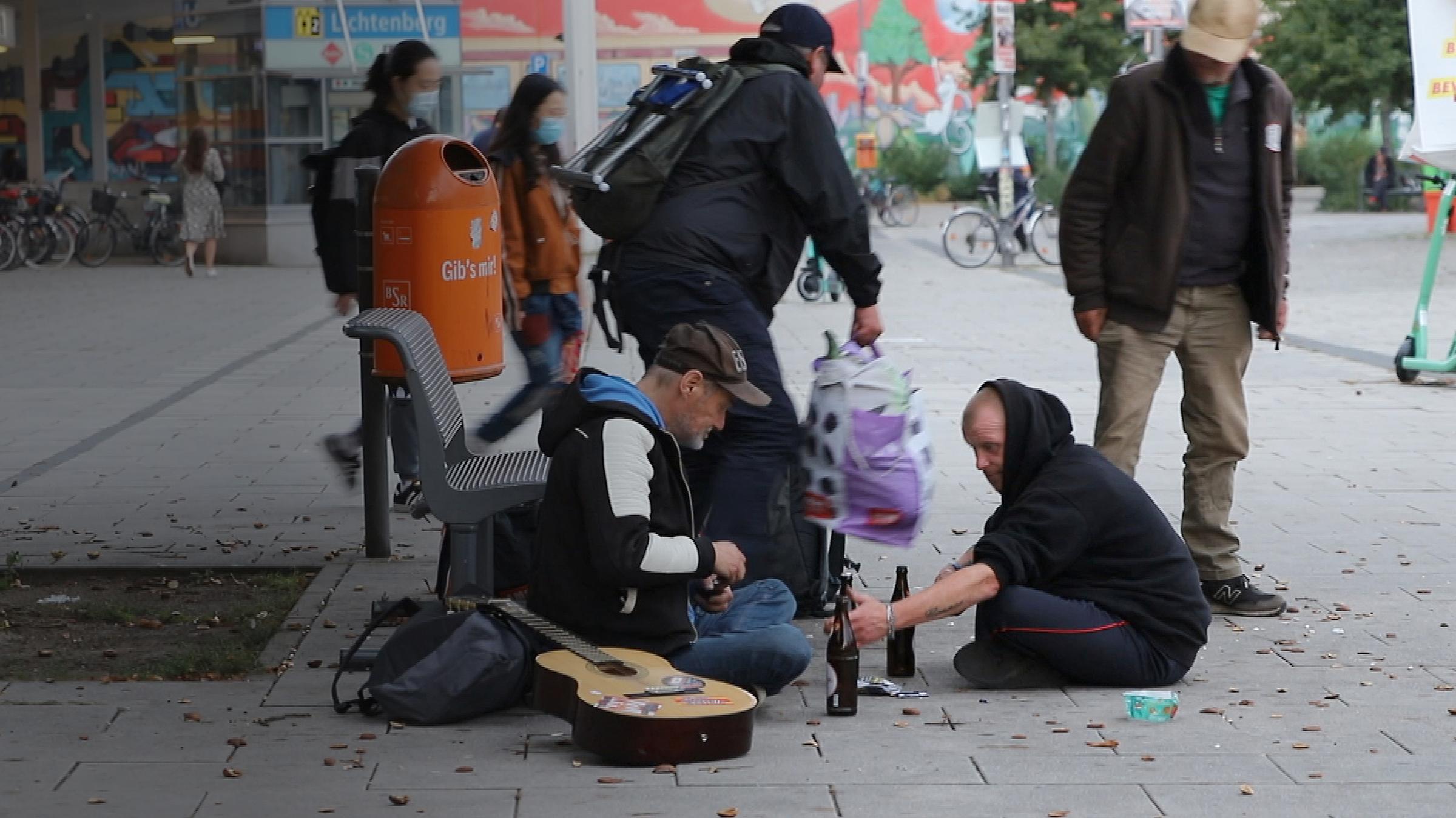 Eine Gruppe von jungen Obdachlosen auf einem Platz. Sie trinken Bier.