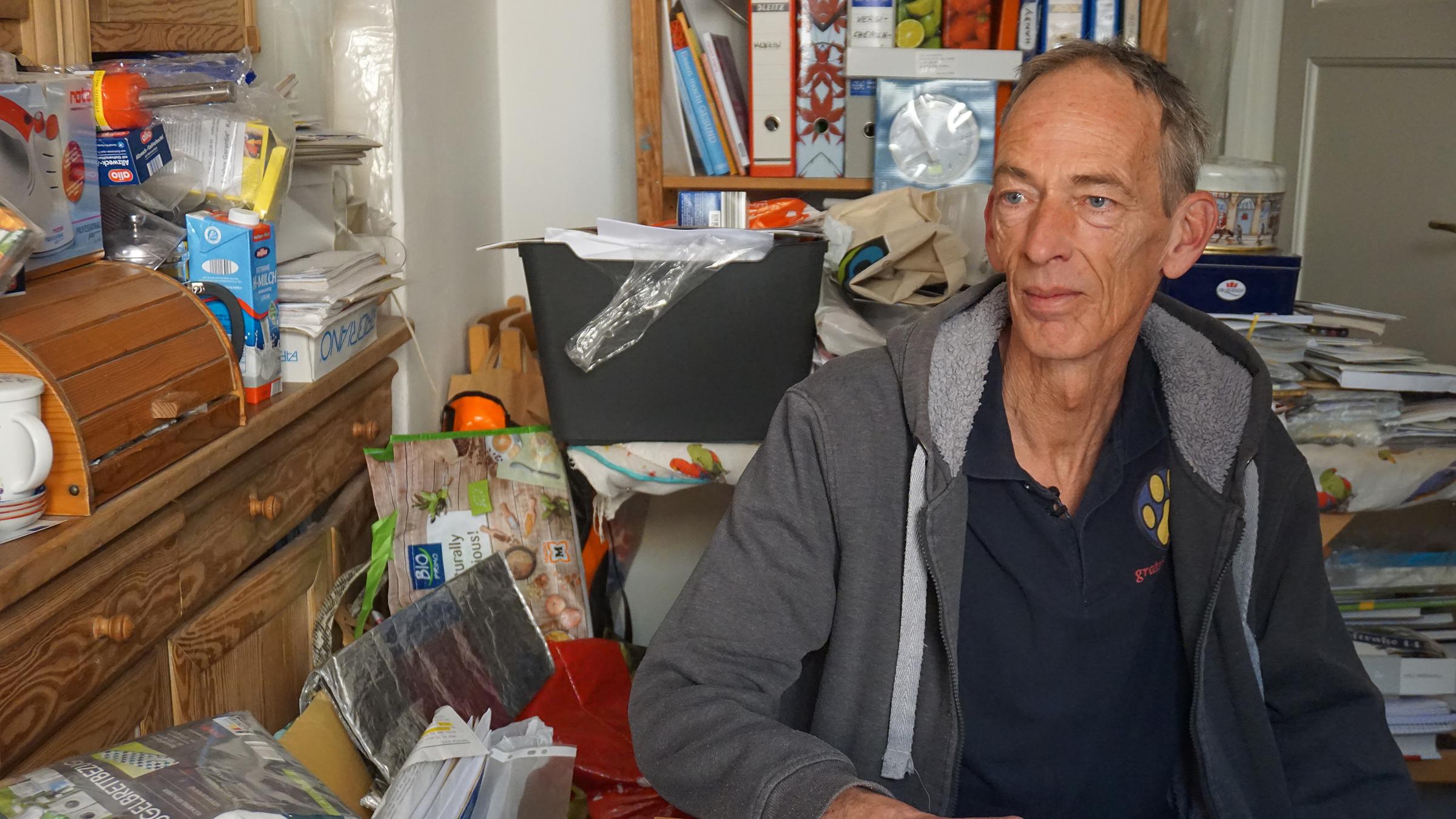 Wedigo von Wedel vom H-Team e.V. sitzt an einem Tisch in einer vollgestellten Küche