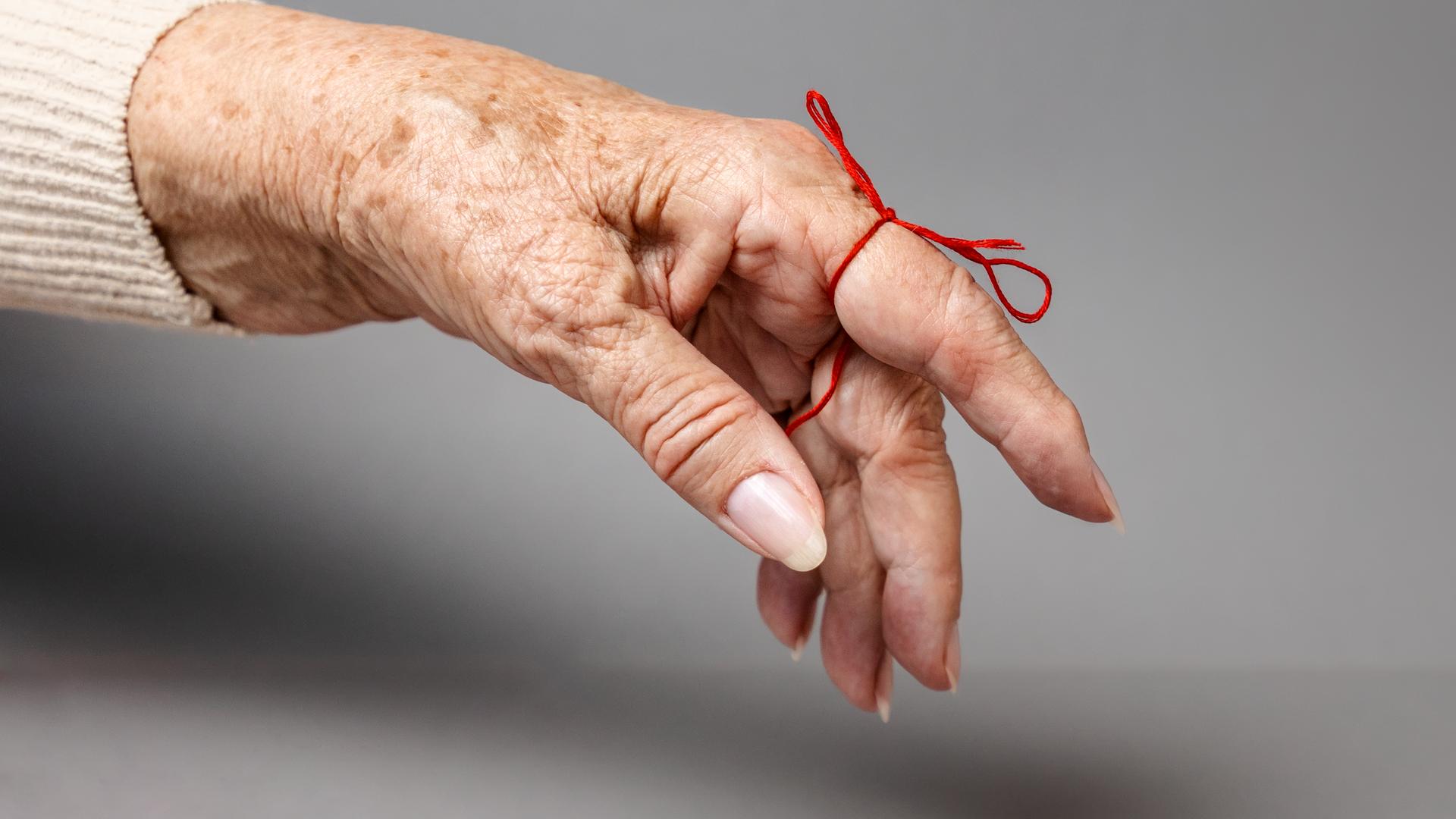 Ausgestreckter Finger mit einer Schleife zur Erinnerung daran. 