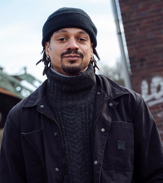 Markus steht vor der Schwebebahn in Wuppertal und schaut in die Kamera.