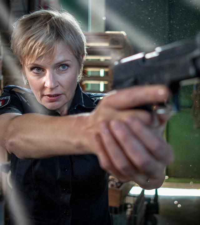 "Notruf Hafenkante - Lebensmüde": Nahaufnahme von Melanie Hansen (Sanna Englund), die mit ihrer Waffe auf etwas vor sich zielt.