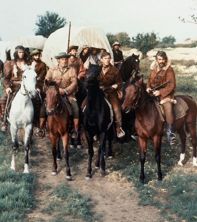 Abiram Bush (Mircea Pascu, l.), Nat Bumppo (Hellmut Lange, 2.v.l.), Miles Forman (Helmuth Schneider, 2.v.r.) und Chingachgook (Pierre Massimi, r.) beraten über den Weg des Siedlertrecks.