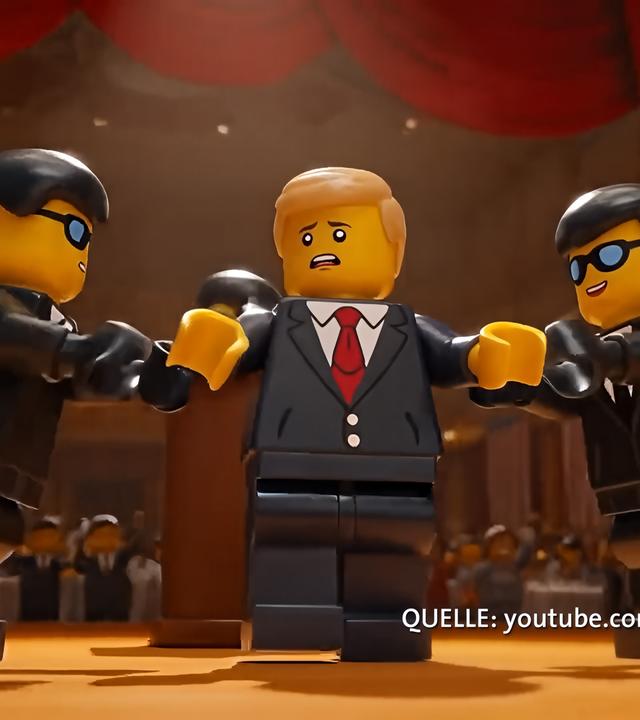 Zwei dunkelhaarige Lego-Männer in Anzügen halten einen blonden Lego-Mann mit Anzug und roter Kravatte von beiden Seiten fest.
