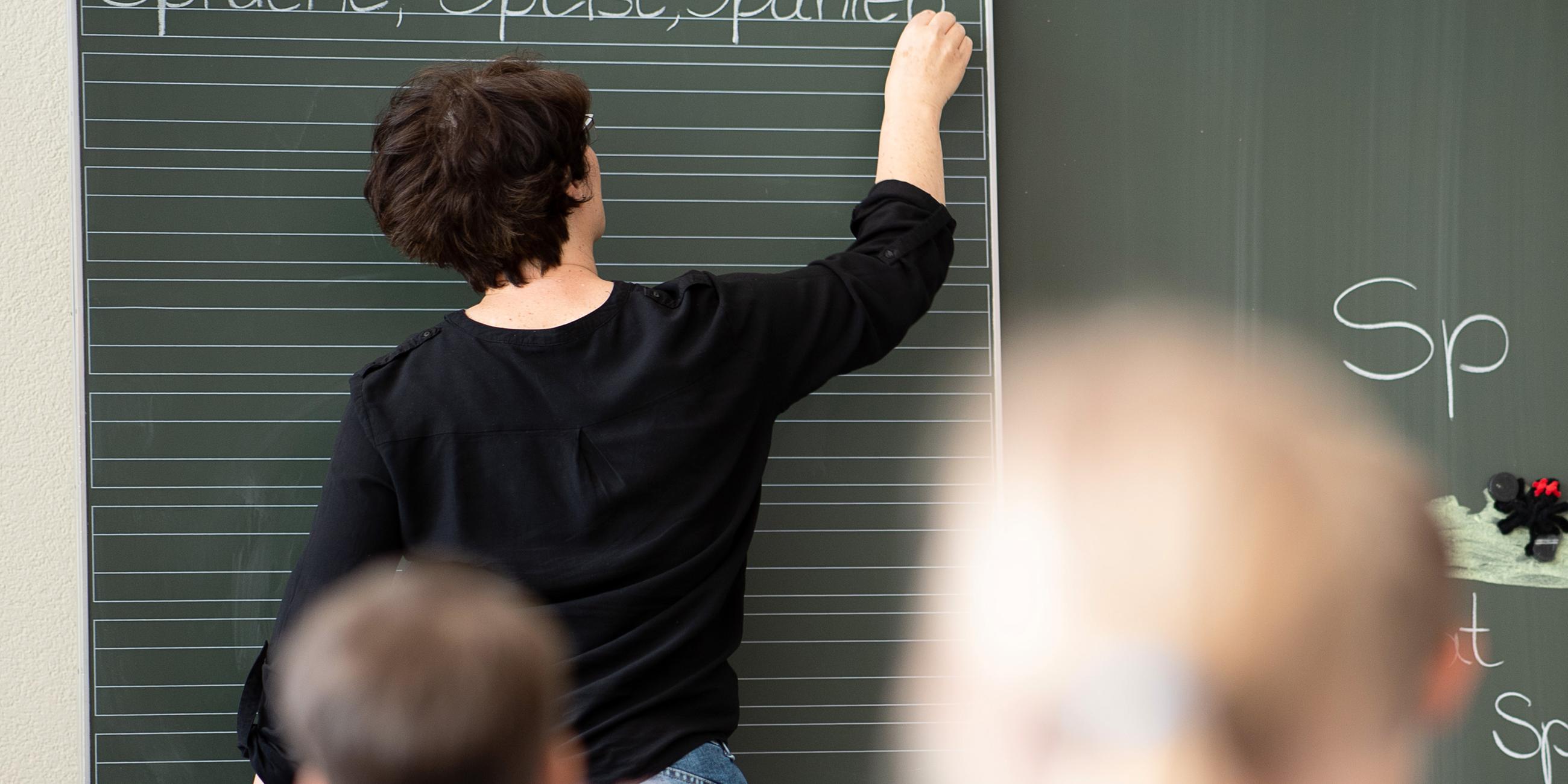 Archiv: Eine Lehrerin schreibt in einer Schule Worte an eine Tafel. 